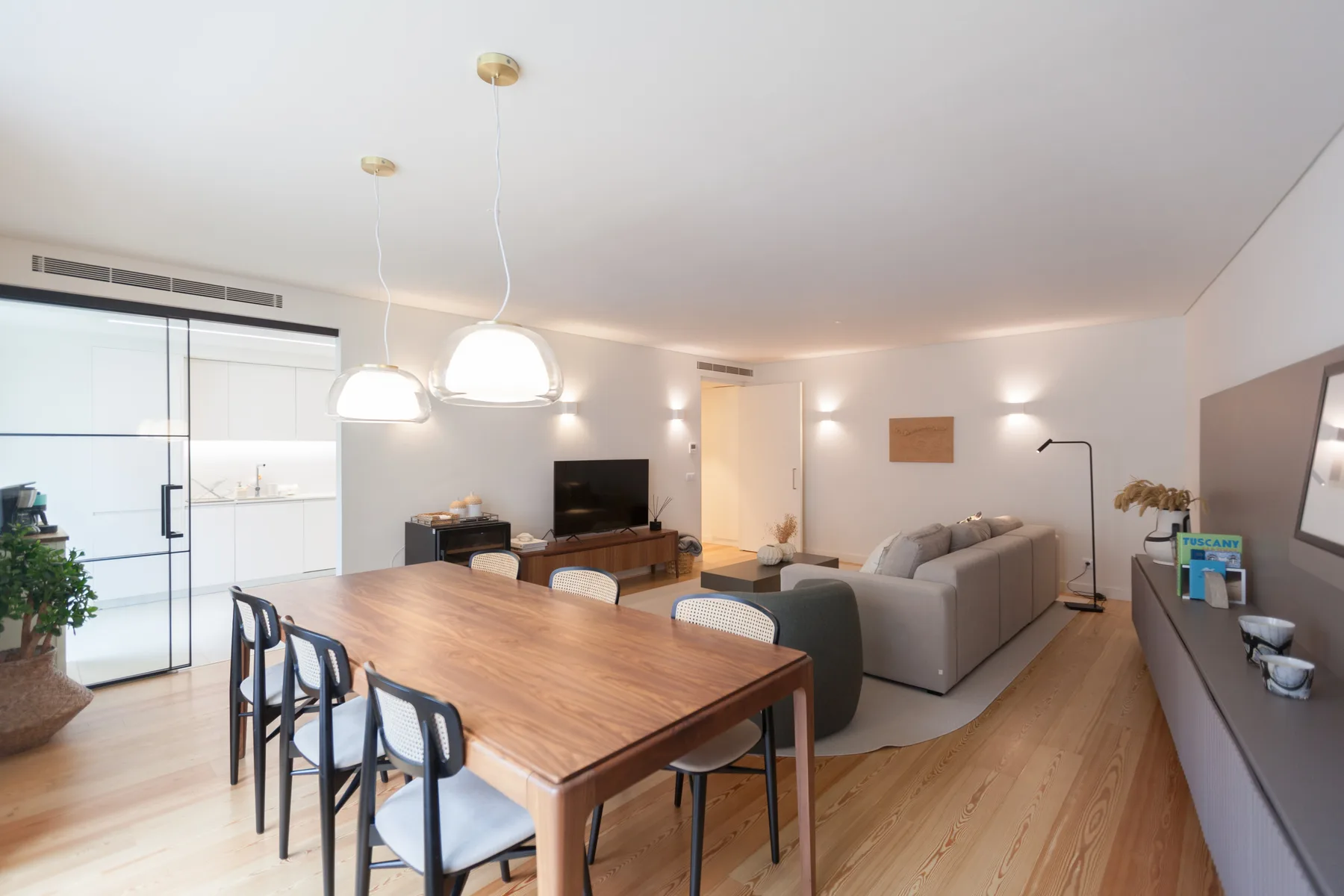Una zona de comedor y sala de estar con mesa de madera, asientos y televisor.