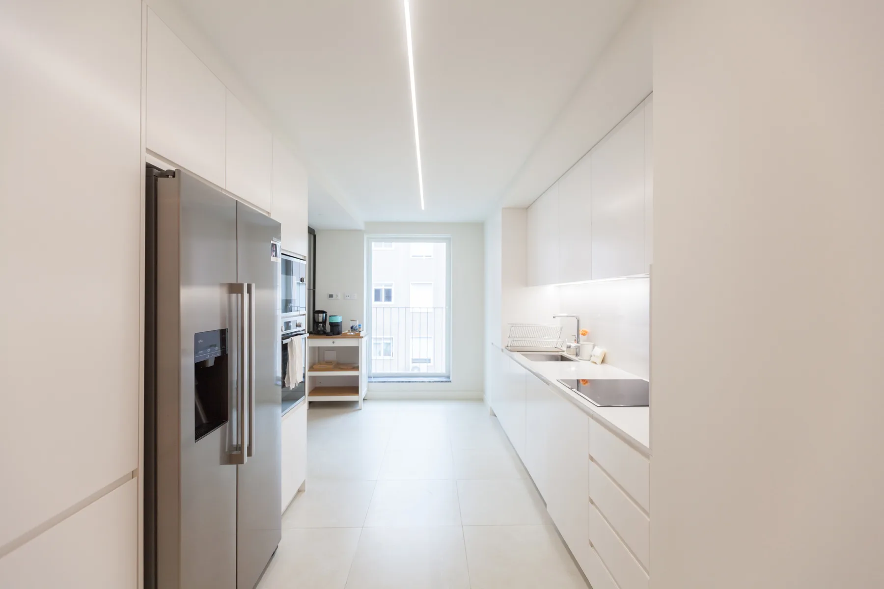 Una cocina moderna y luminosa con electrodomésticos de acero inoxidable y armarios blancos.
