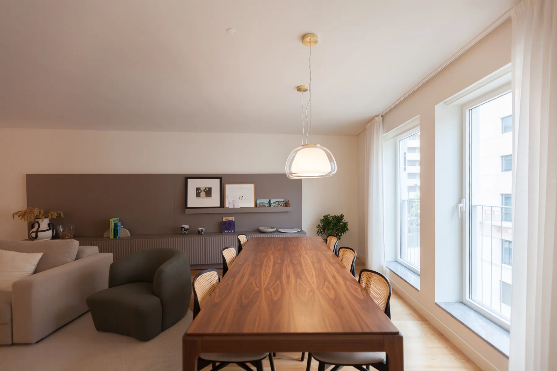 Comedor con una mesa larga de madera junto a grandes ventanas.