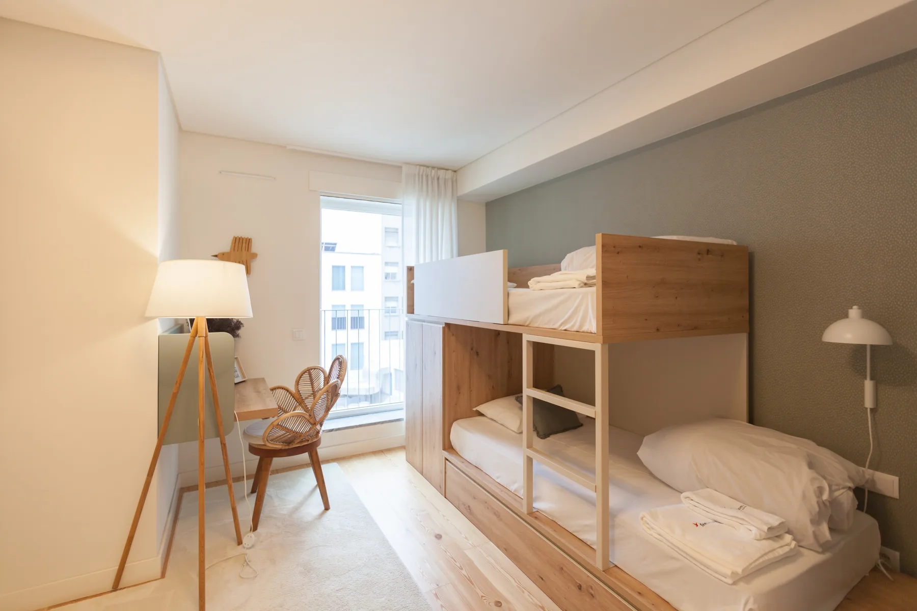 Un dormitorio luminoso con literas de madera y una ventana.