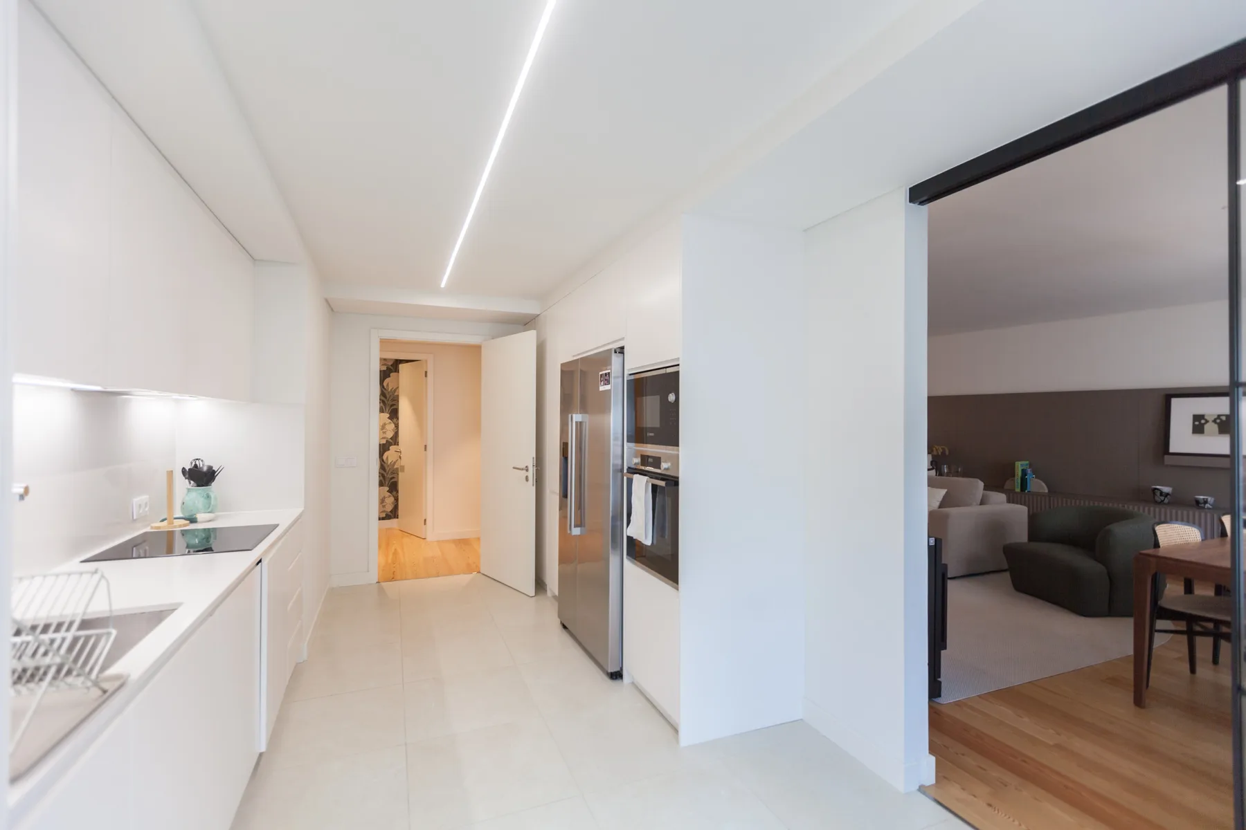 Una cocina moderna se abre a una sala con asientos y una mesa de comedor.