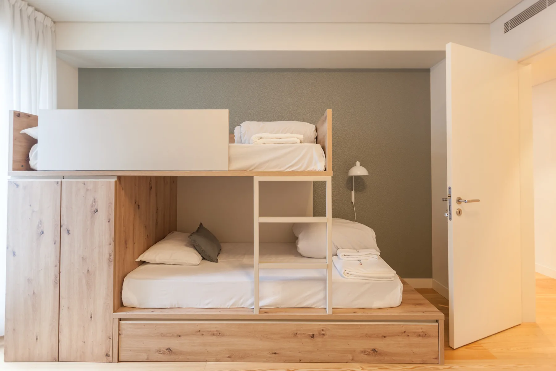 Un dormitorio con una litera de madera y ropa de cama blanca.