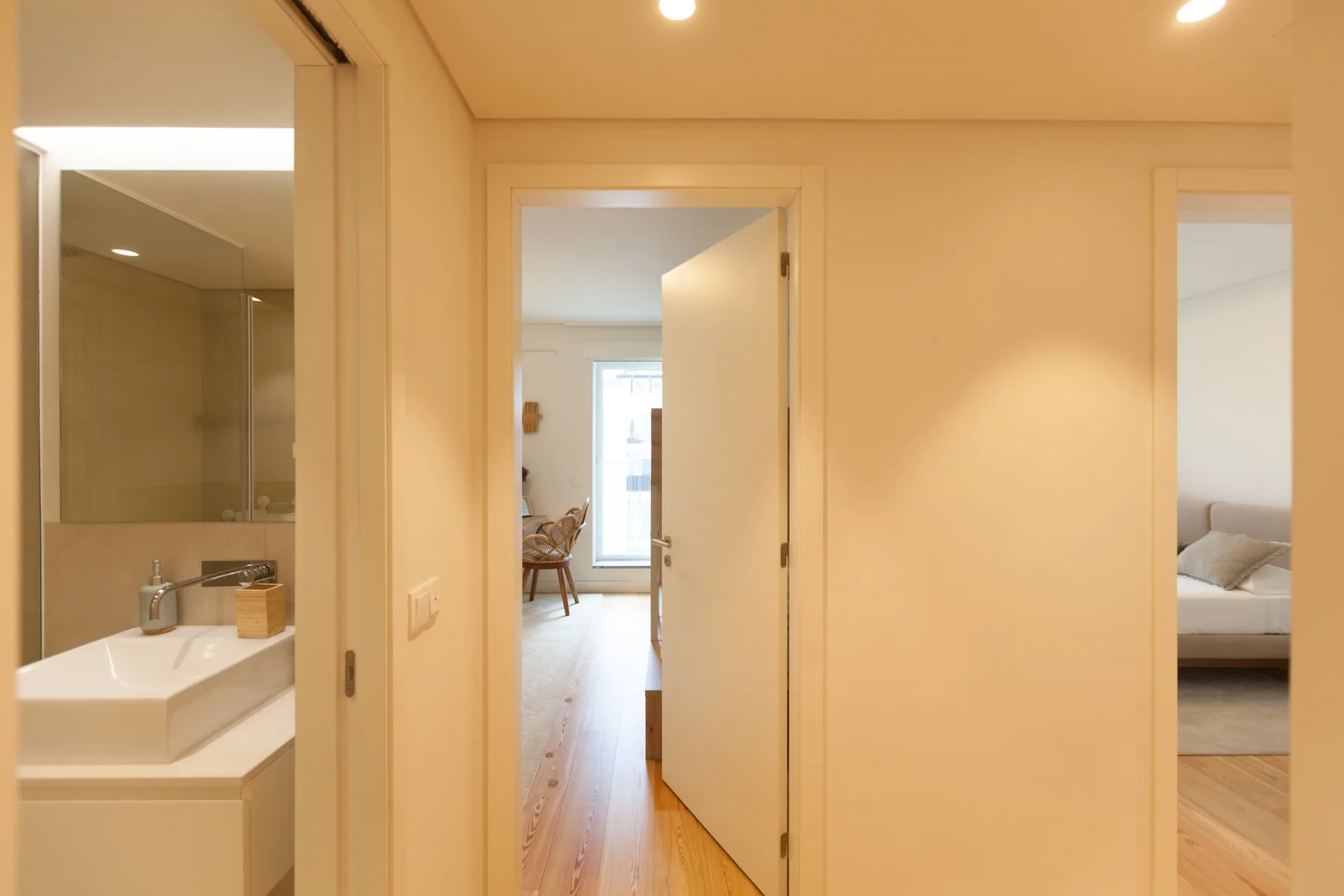 Un pasillo con puertas abiertas que dan a un baño y un dormitorio.