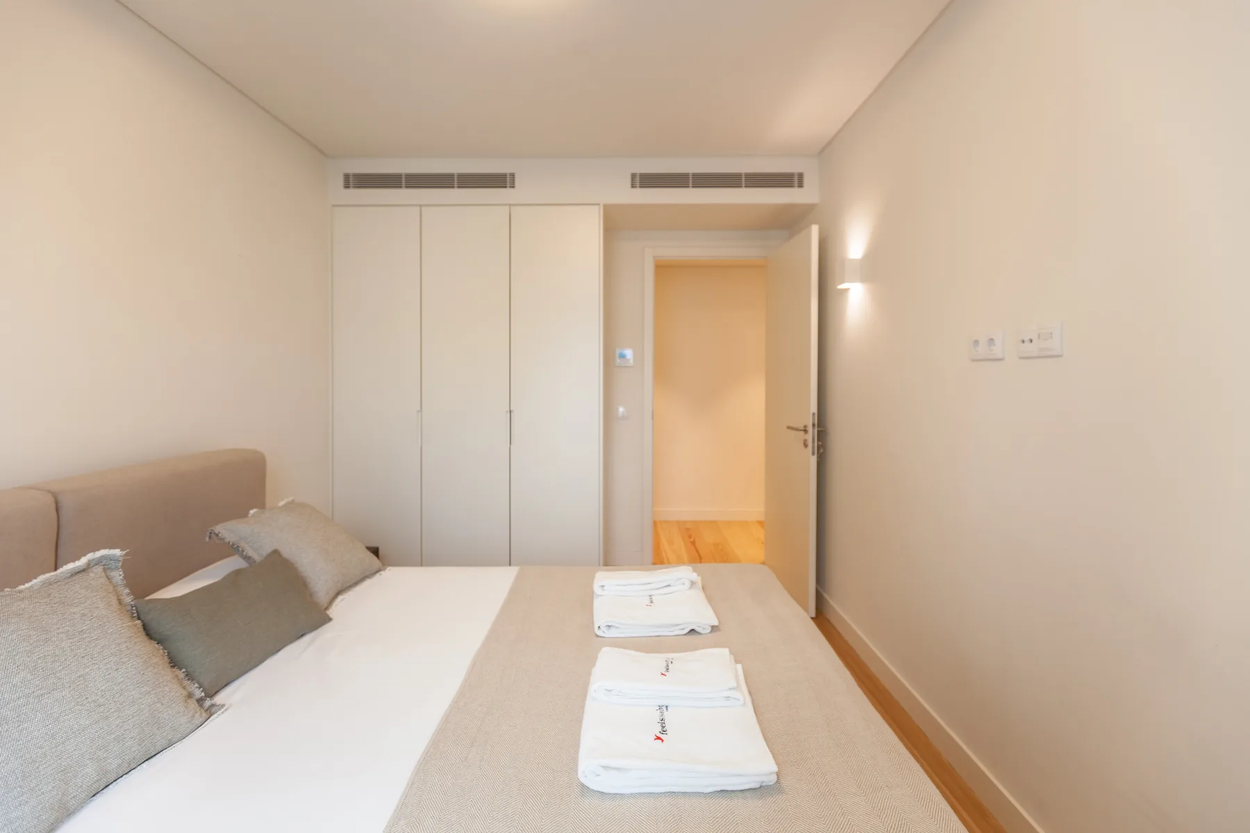 Un dormitorio con una cama, armarios empotrados y una puerta abierta.