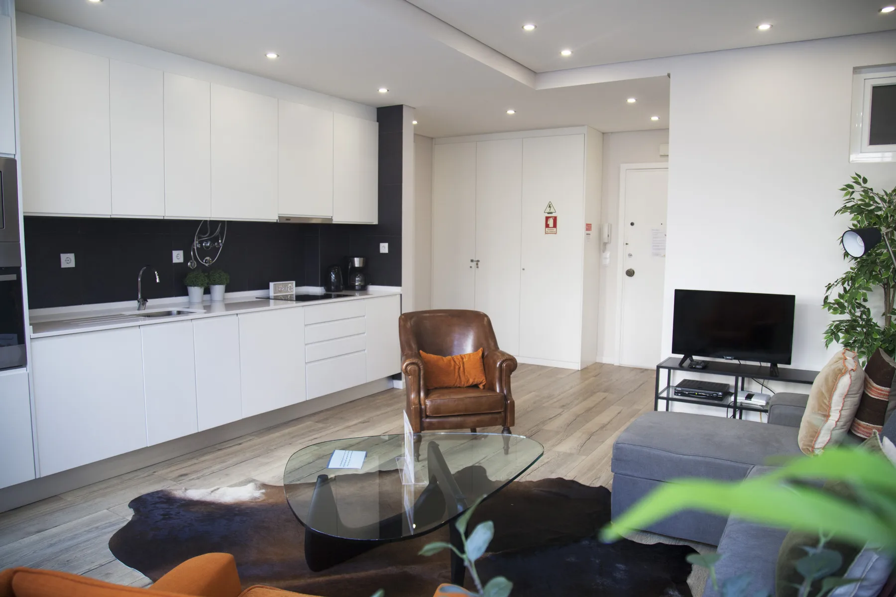 A bright living room with a glass coffee table and television.