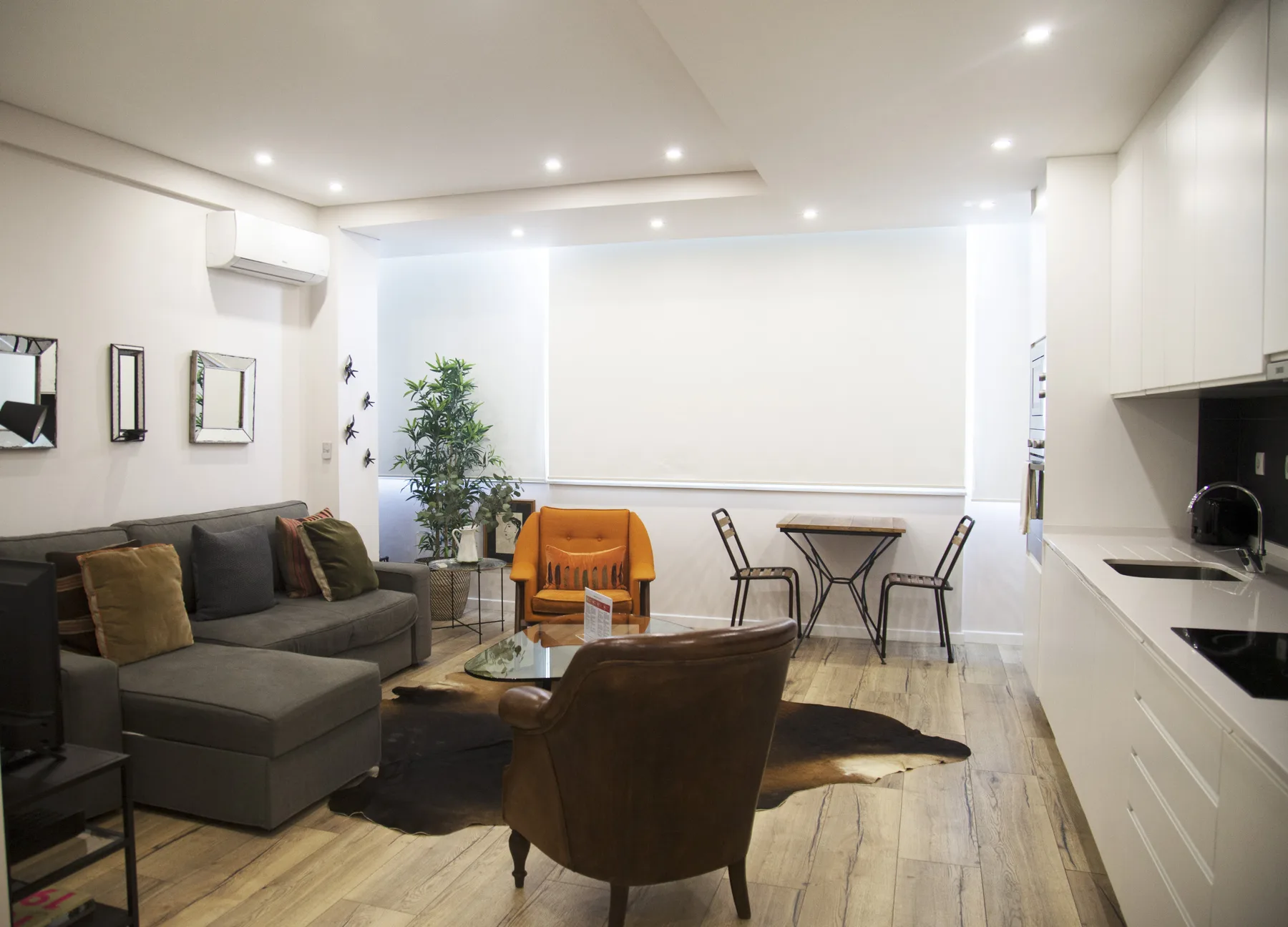 A bright open-plan living and dining area has seating beside a compact dining table.