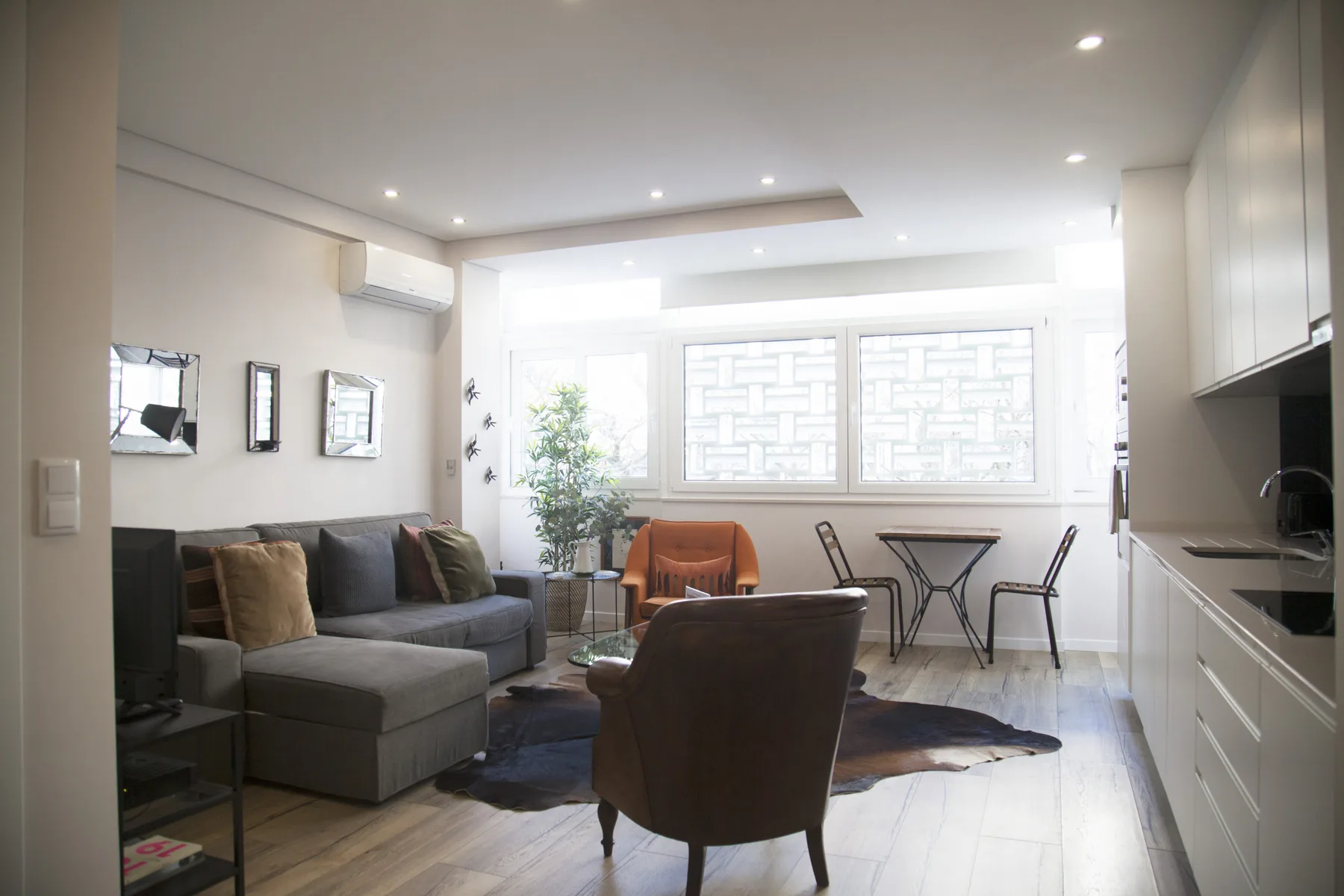 A bright living room with seating, a coffee table, and large windows.