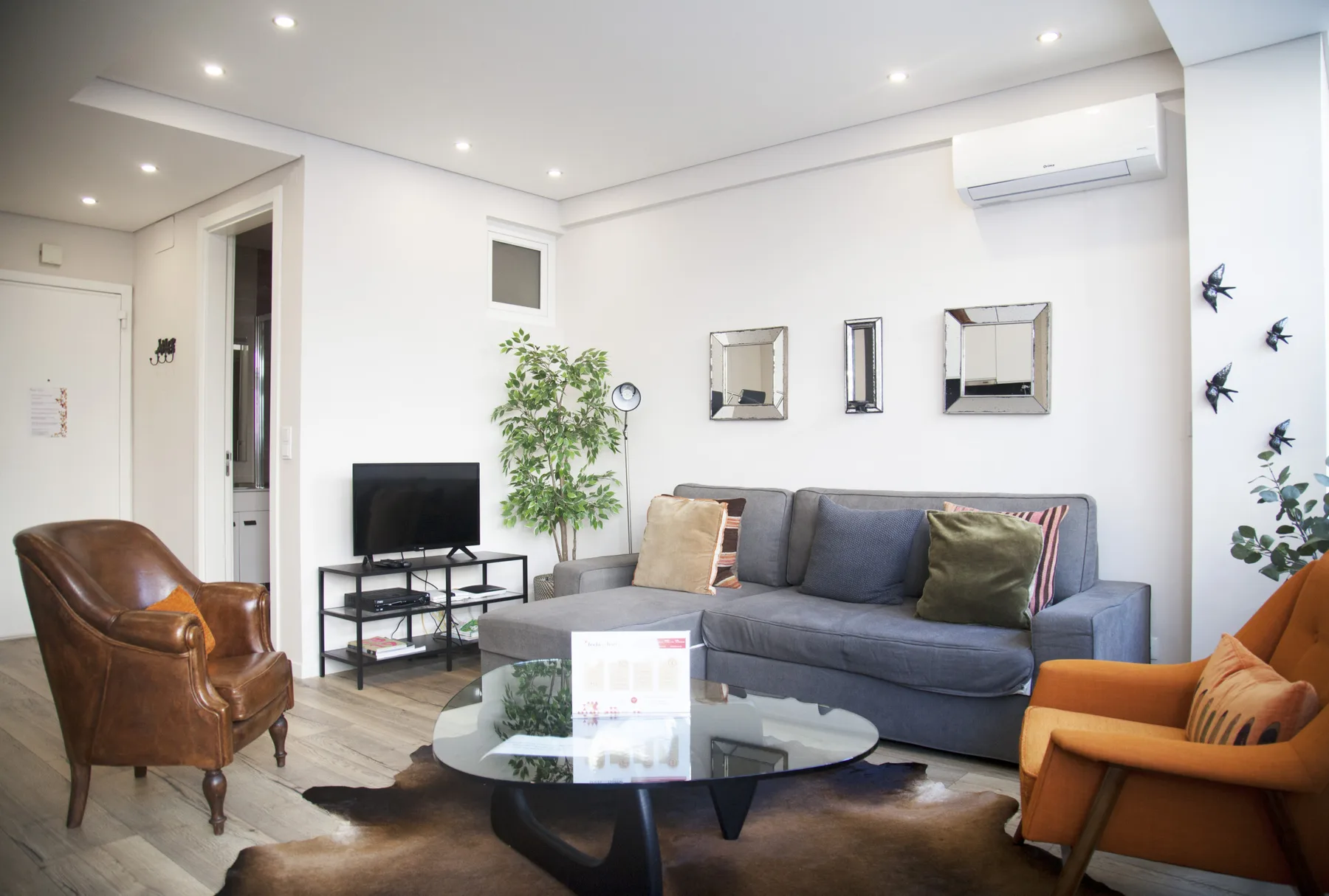 A living room with a gray sofa, armchairs, and a glass coffee table.