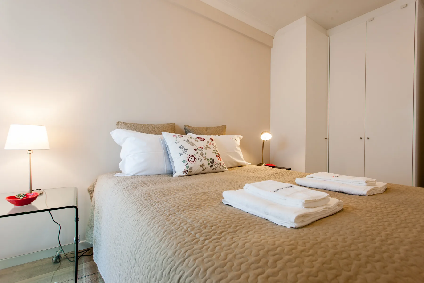 A bedroom with a neatly made bed and folded towels.