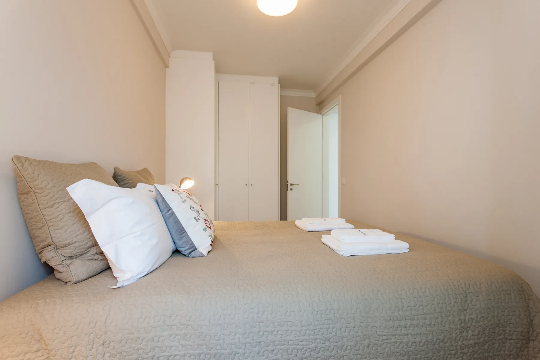A bedroom with a neatly made bed and an open door.