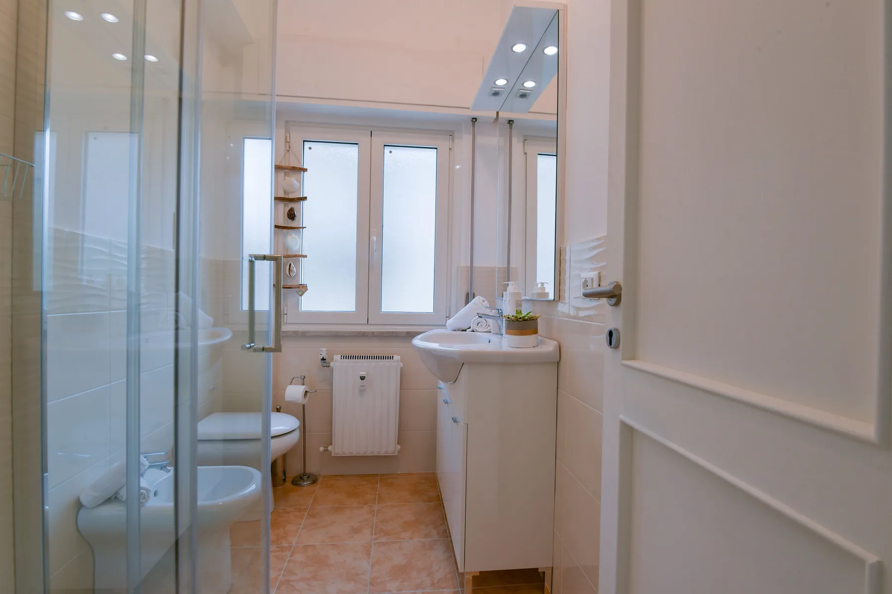 Un baño luminoso con ducha de vidrio, lavabo y ventana.