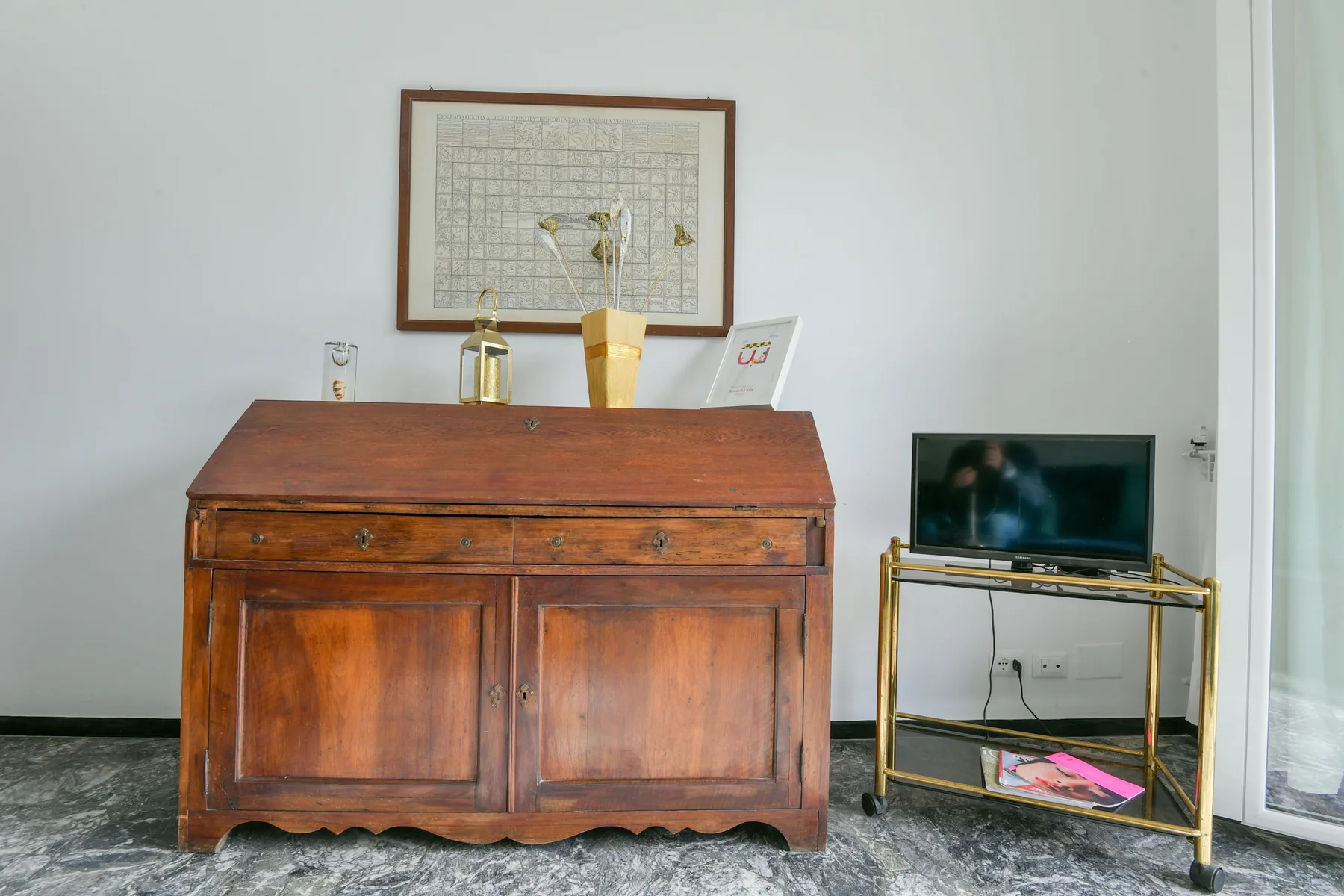 Un mueble de madera está junto a un televisor sobre un soporte metálico.