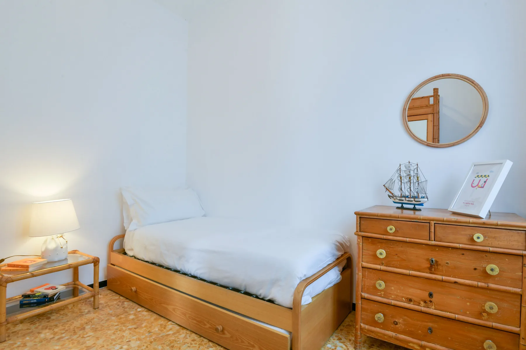Un dormitorio luminoso con una cama de madera y una cómoda al lado.