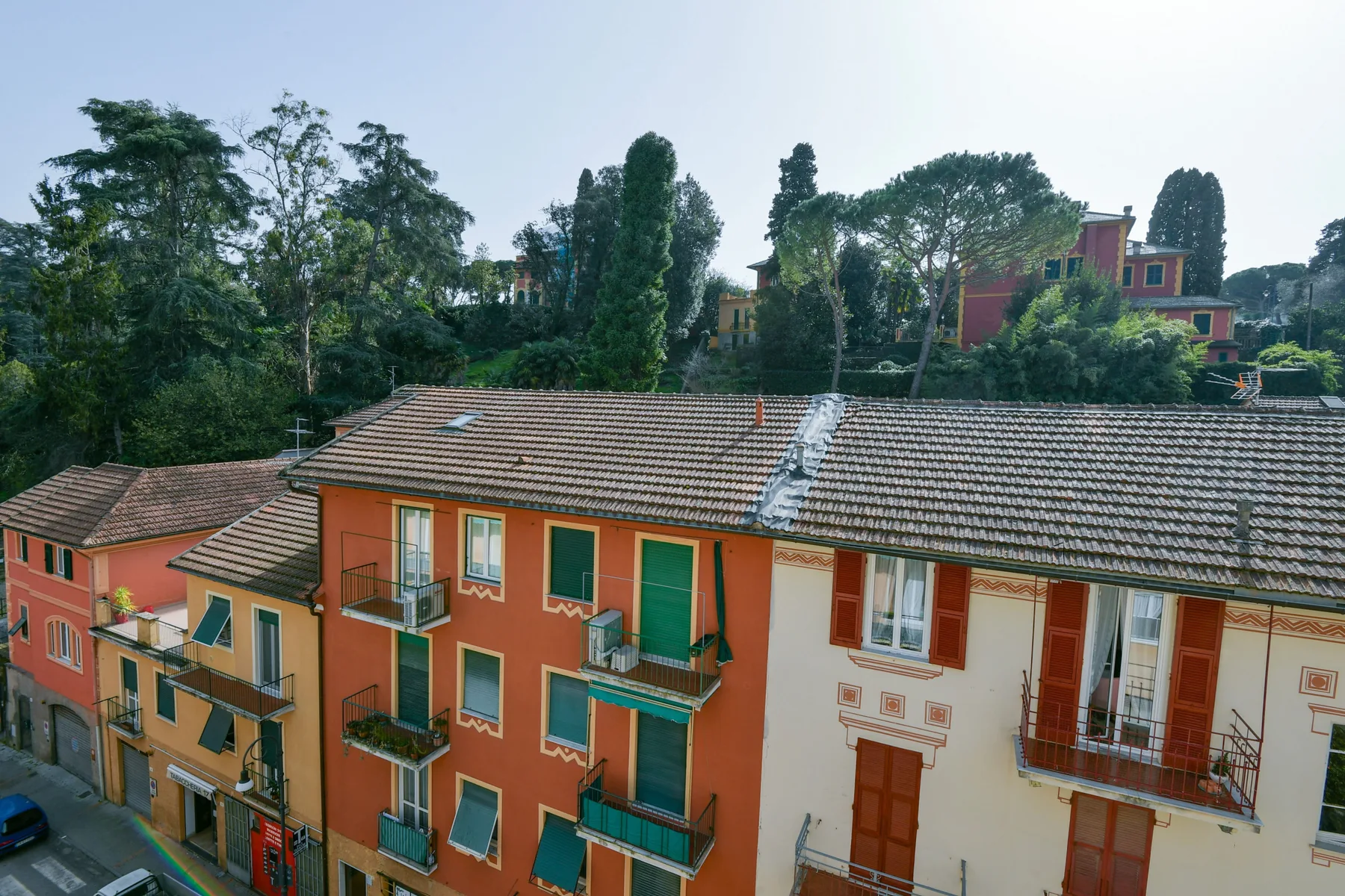 Edificios residenciales coloridos con balcones se alzan entre árboles bajo un cielo pálido.