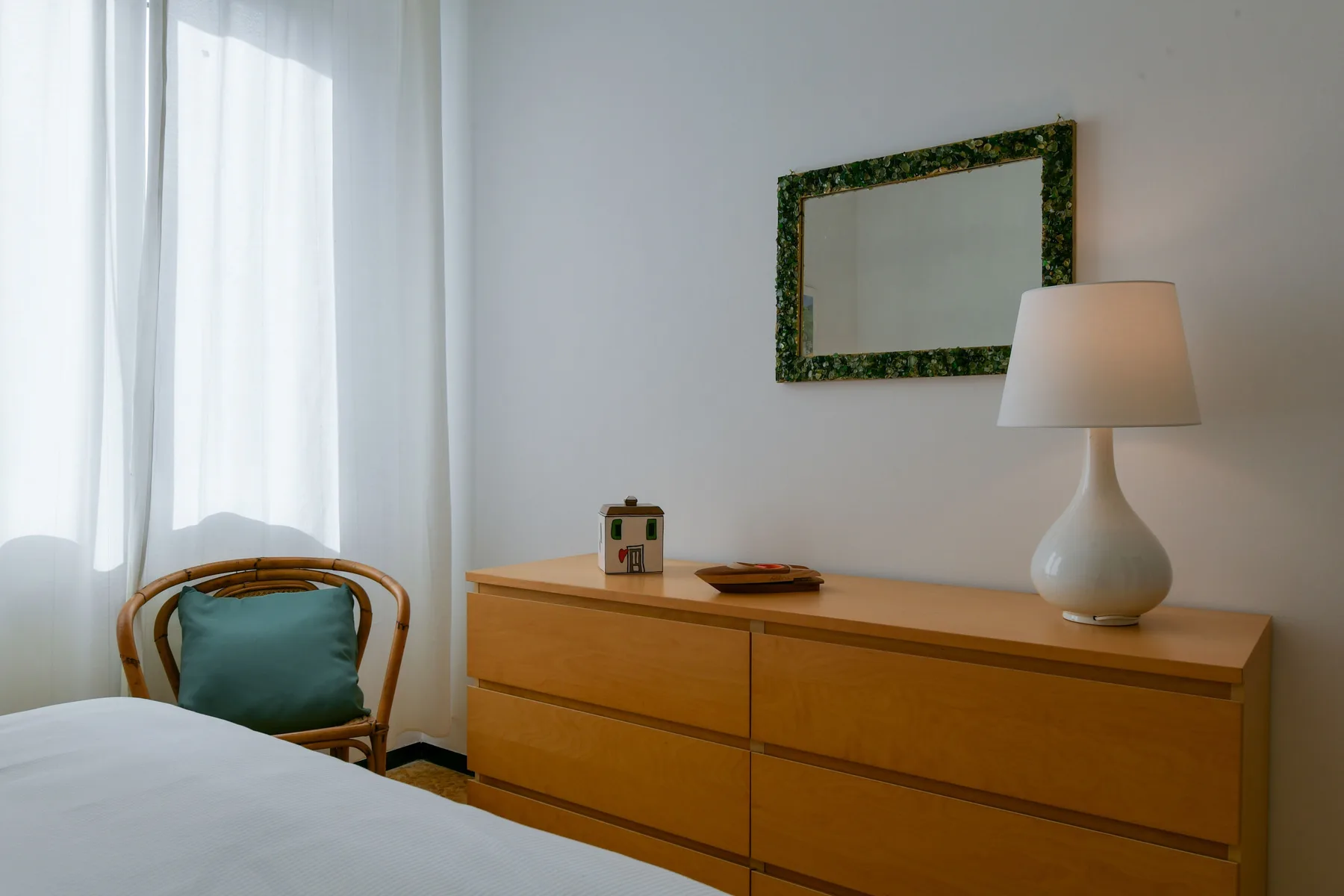 Un dormitorio con una cama, una cómoda de madera y una lámpara junto a una ventana.