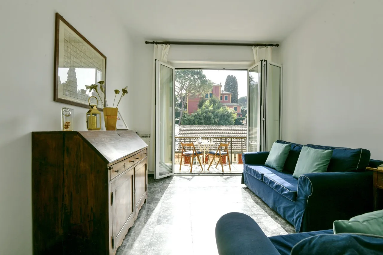 Una sala luminosa con asientos junto a puertas abiertas a un balcón.