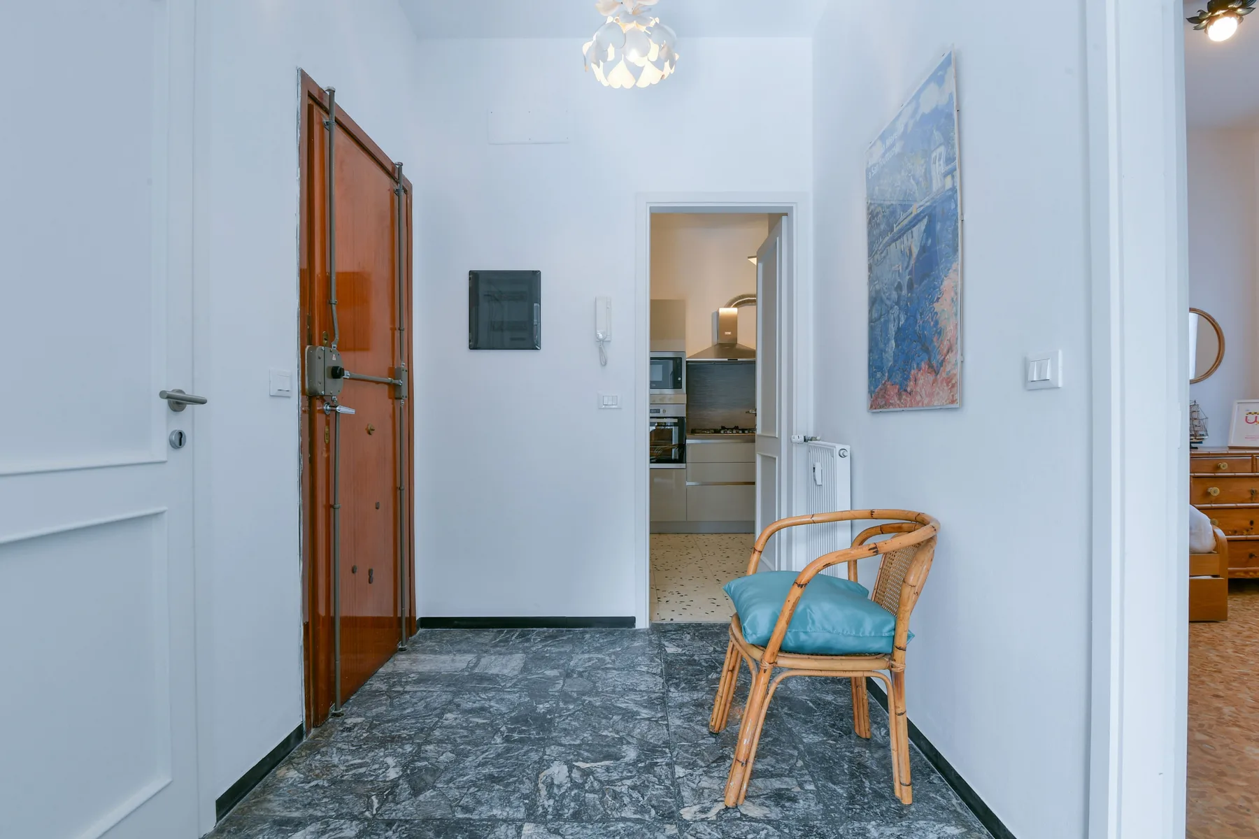 Un recibidor luminoso con una puerta de madera y una silla de mimbre.