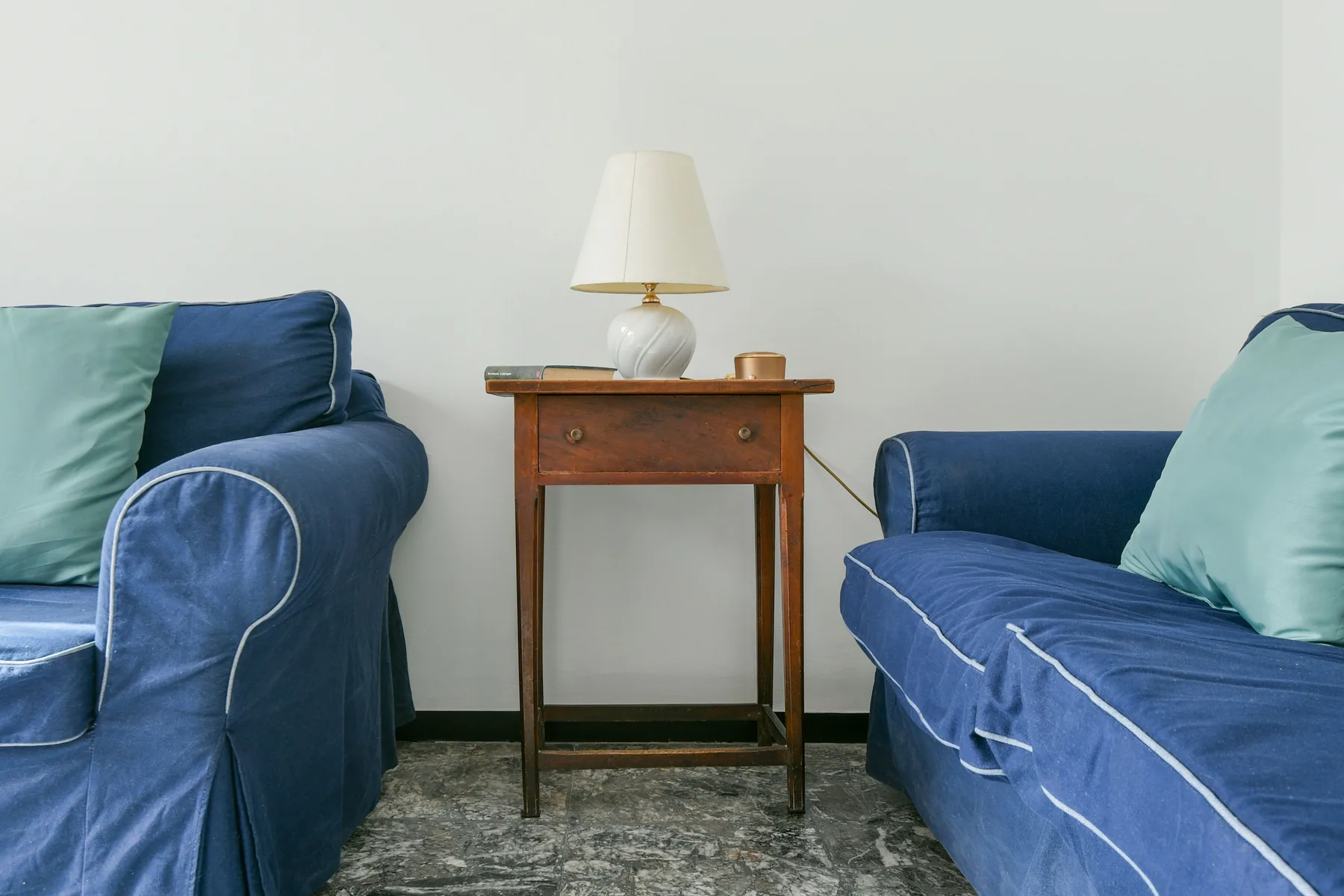 Una zona de estar con asientos azules y una pequeña mesa de madera entre ellos.