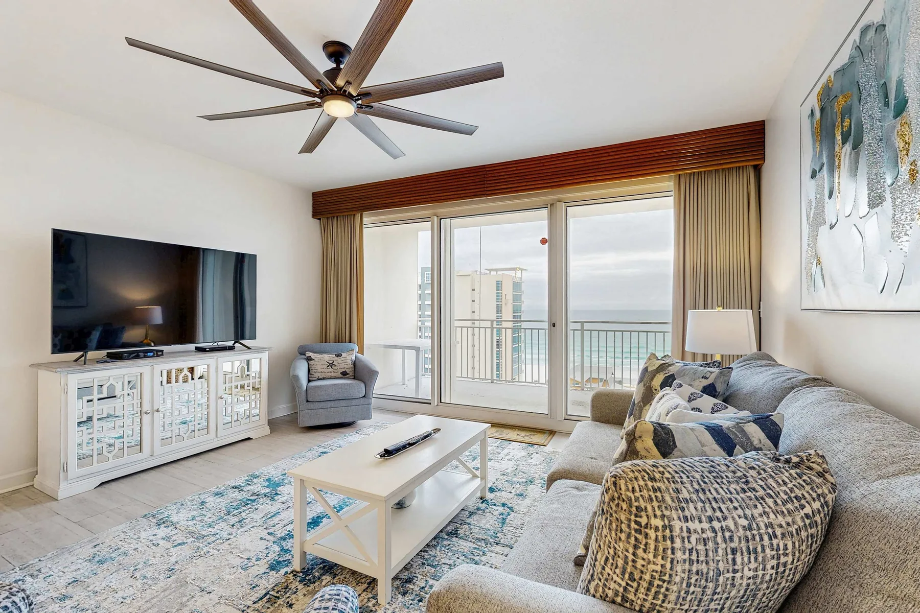 Una sala de estar con asientos, un televisor y puertas de vidrio que dan a un balcón.