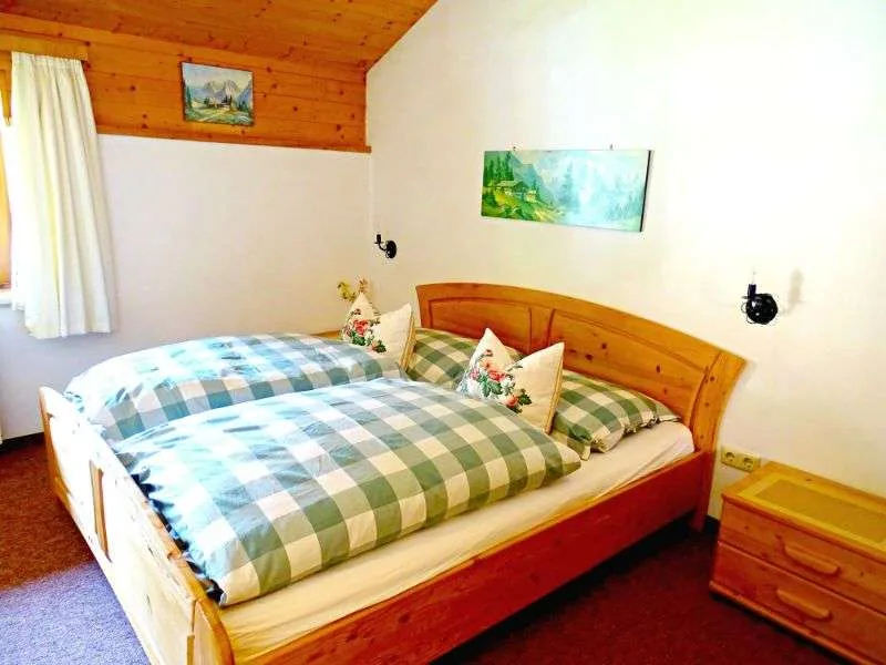 A bedroom with a wooden bed dressed in green and blue checked bedding.
