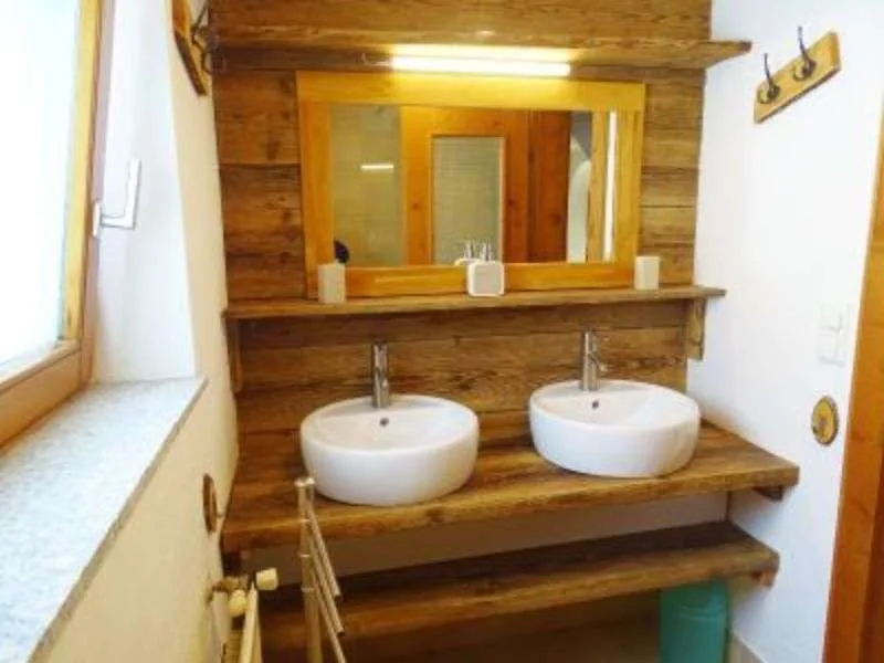 A bathroom vanity with two white sinks beneath a large mirror.