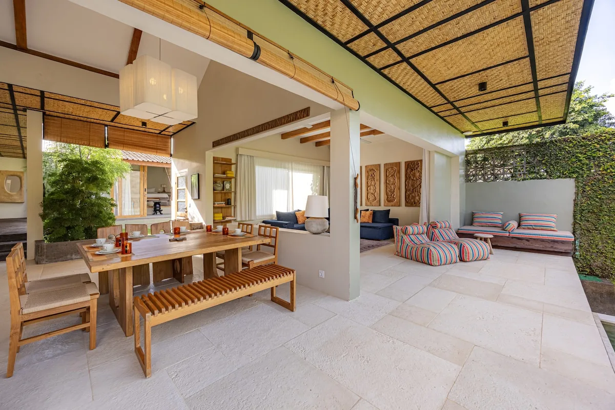 A covered outdoor dining and lounge area opens onto a paved patio.