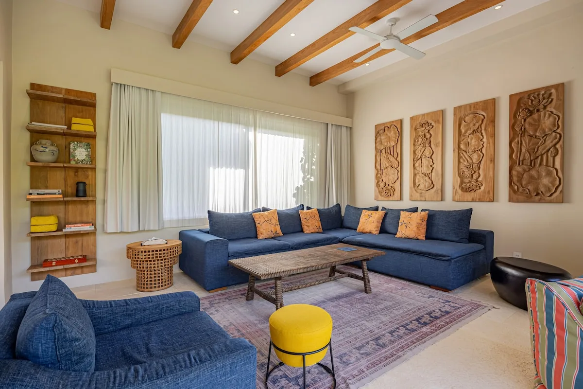 A living room with blue seating, a coffee table, and carved wall panels.