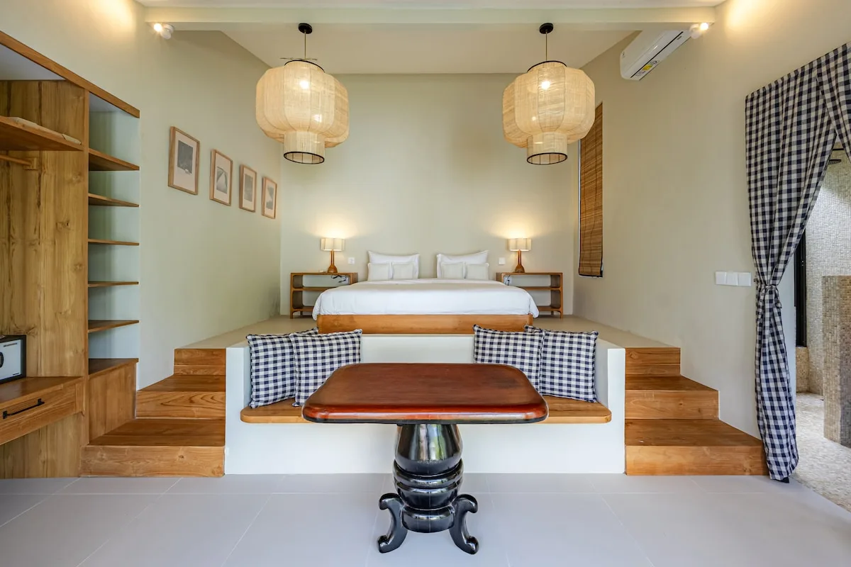 A bedroom with a raised bed, checkered seating, and a small table.