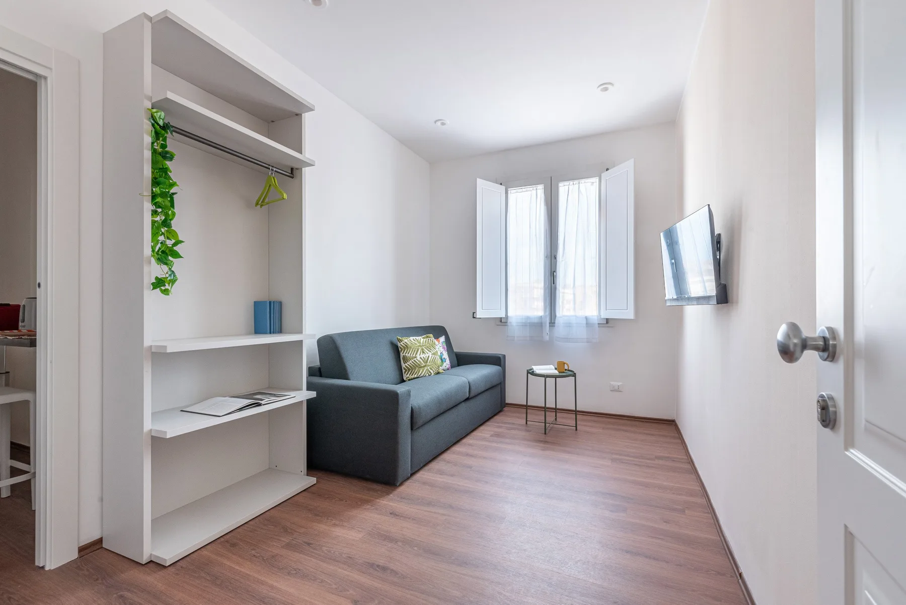 Una habitación luminosa con asientos, estanterías abiertas y una mesita junto a la ventana.