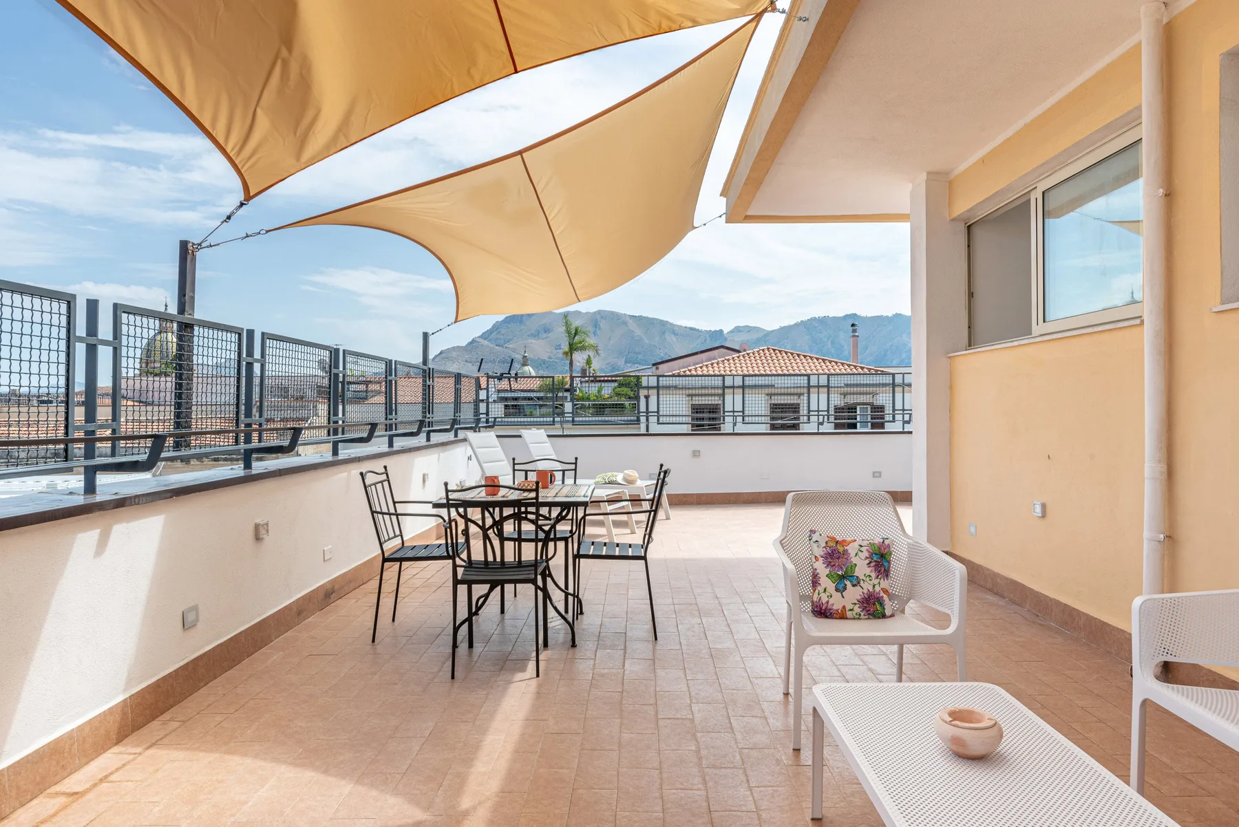 Una terraza en la azotea con asientos al aire libre y un toldo de tela.