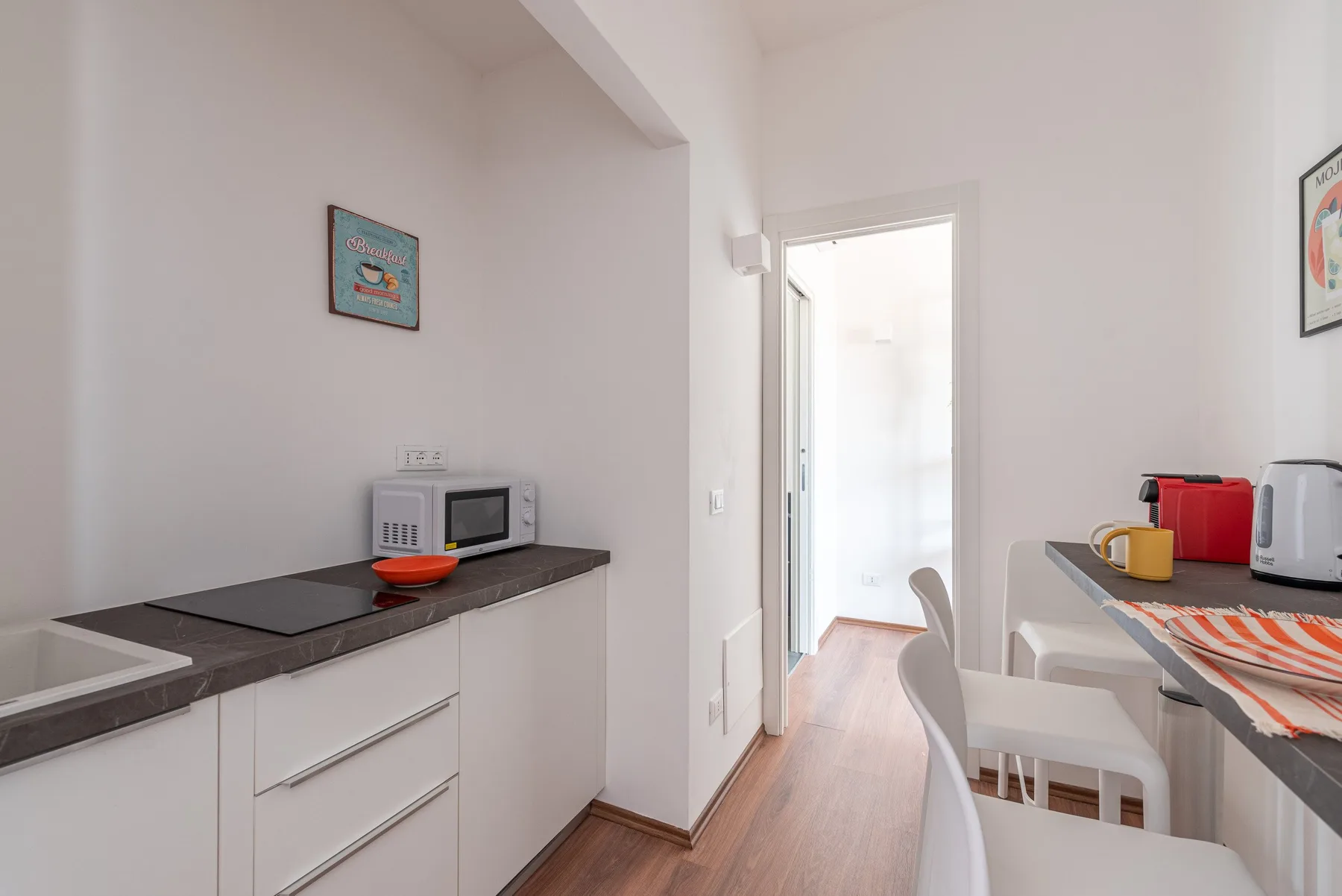 Una cocina luminosa con encimera, microondas y asientos de comedor.