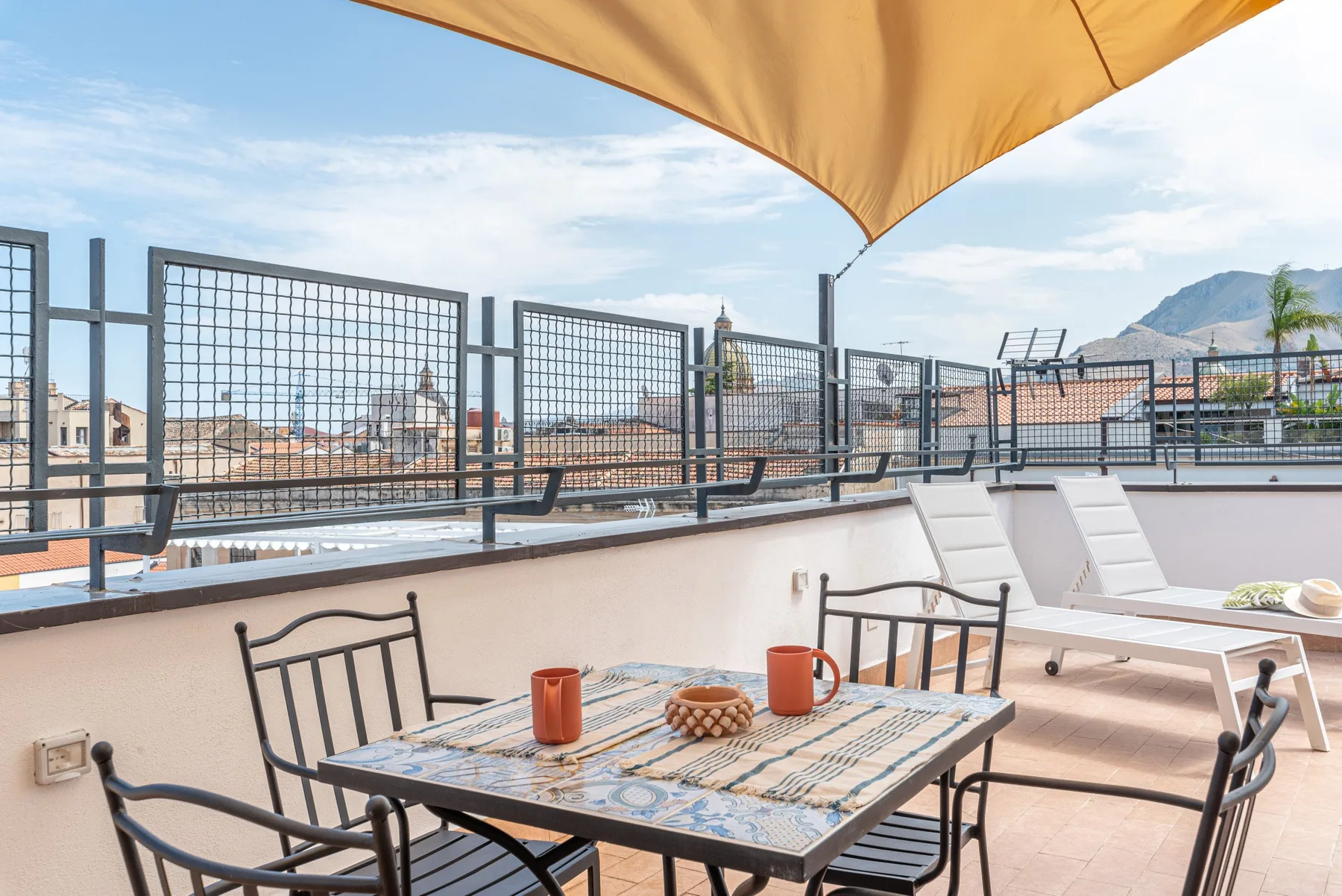 Una terraza en la azotea con una mesa de comedor y sillones bajo un toldo.
