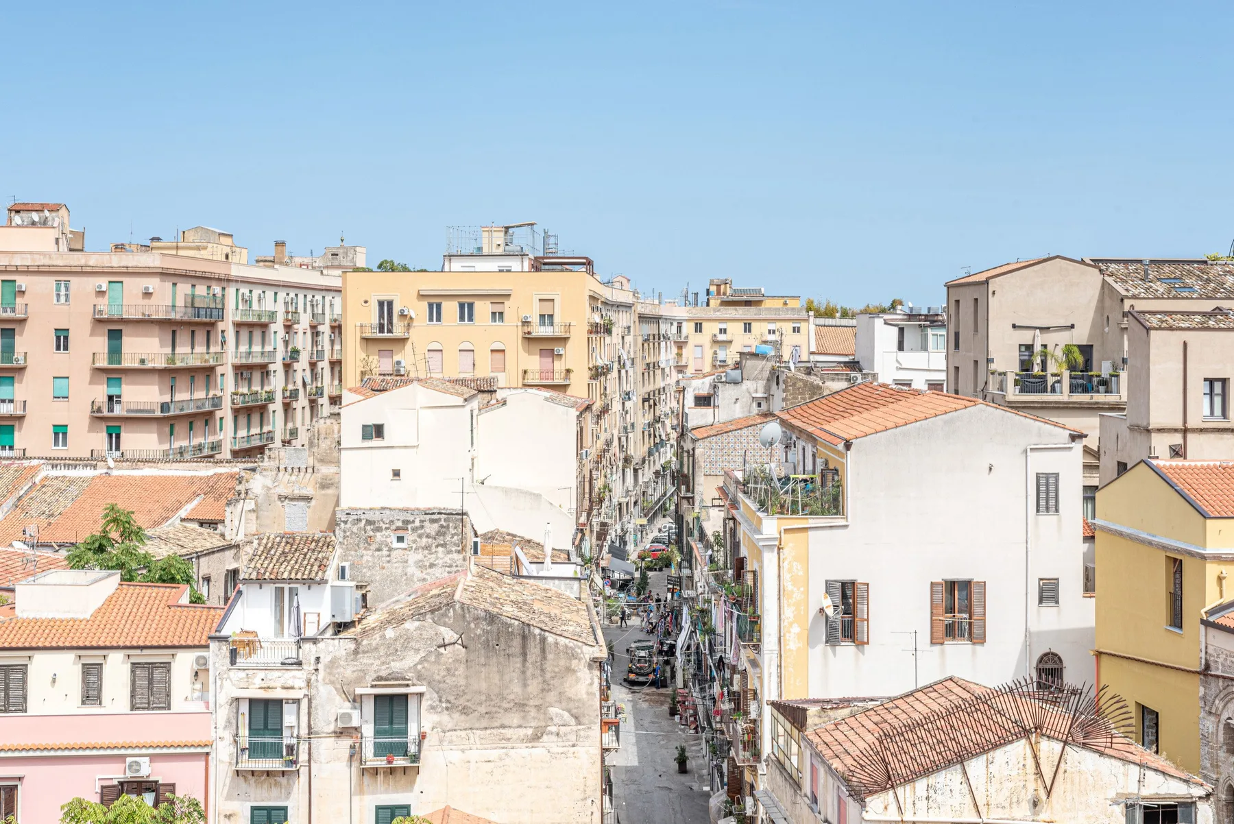 Una calle estrecha de la ciudad pasa entre edificios de apartamentos muy juntos y tejados de tejas.
