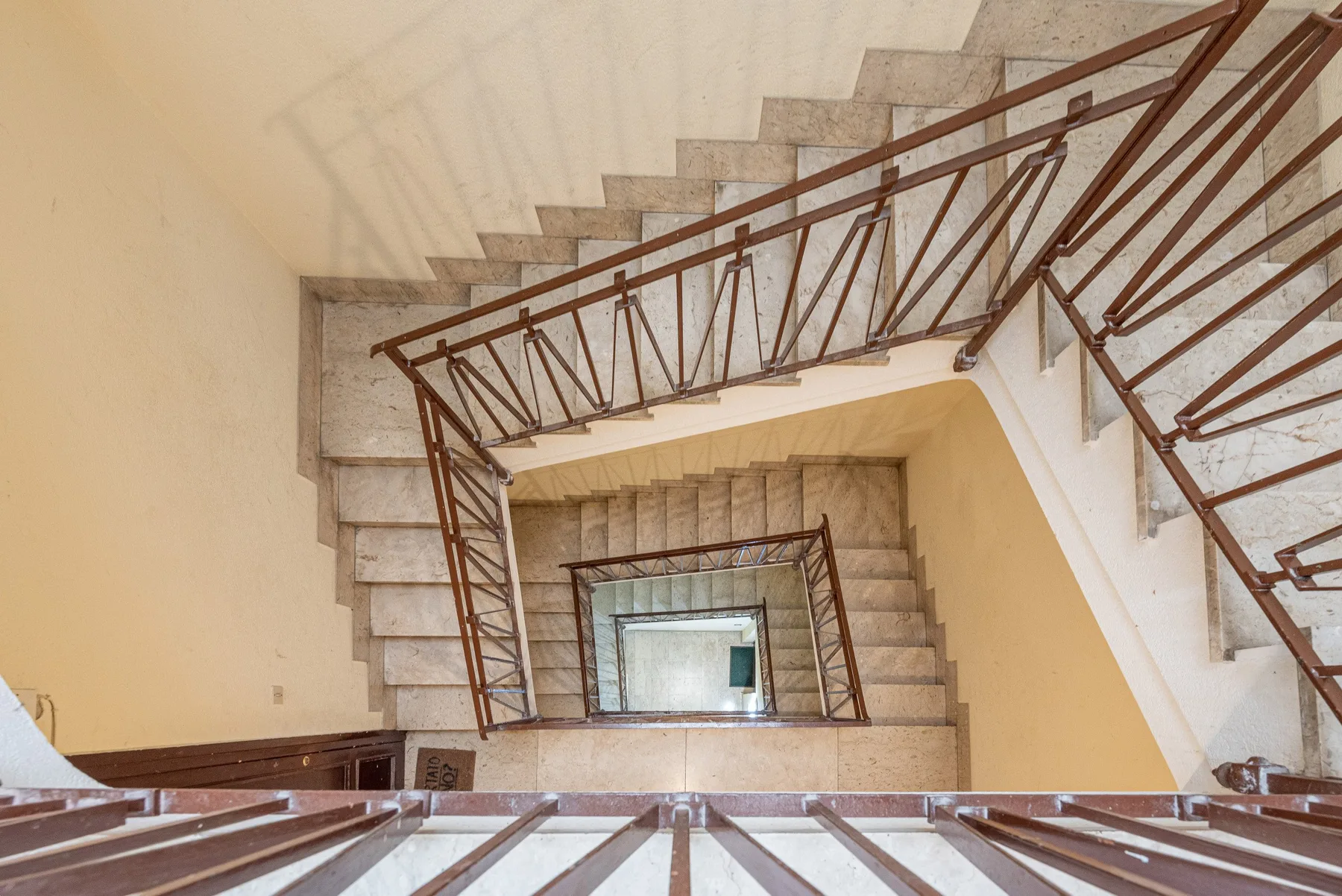 Una escalera con peldaños de piedra y barandillas metálicas marrones.