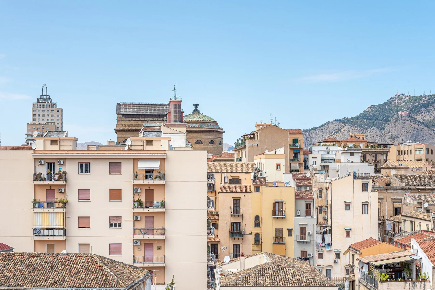Paisaje urbano de edificios próximos entre sí, con una montaña al fondo.