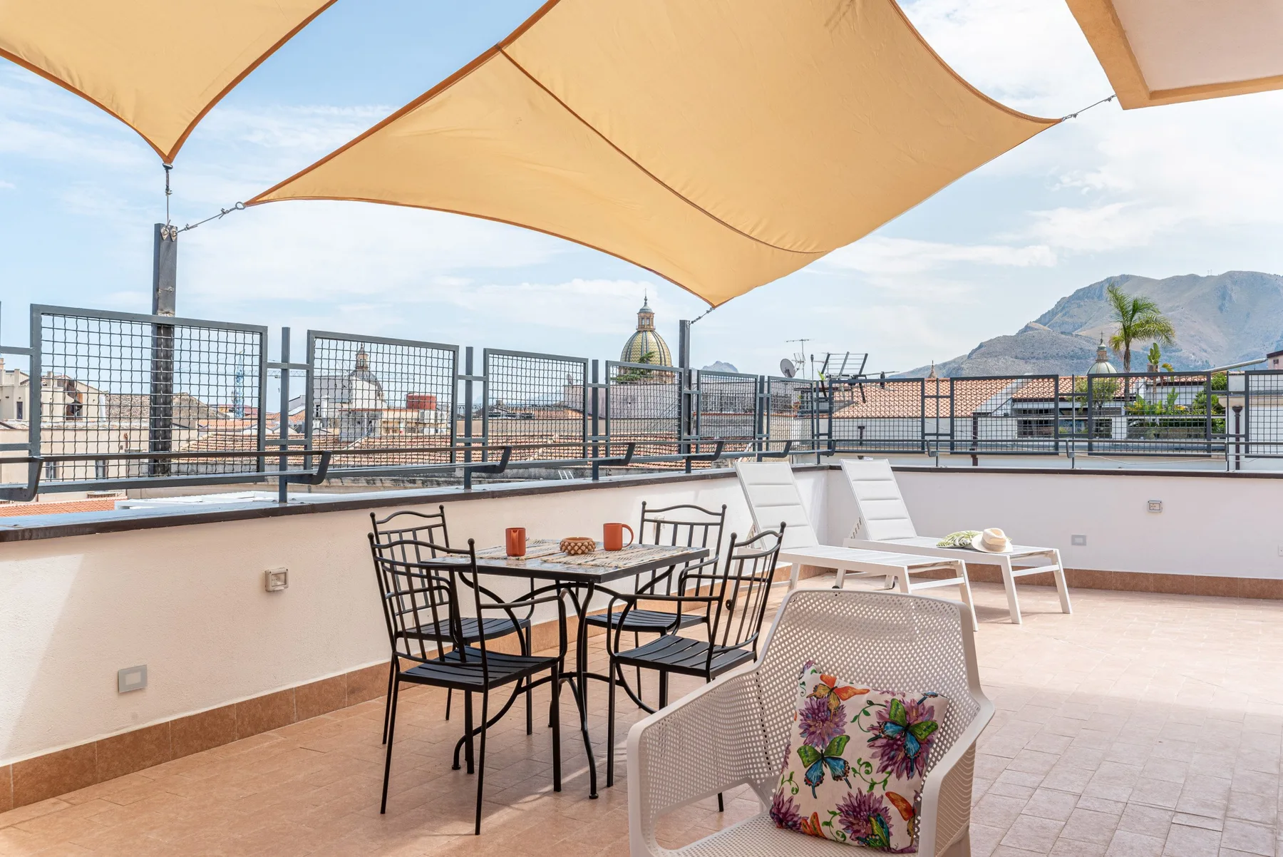 Una terraza en la azotea con asientos de comedor bajo toldos beige.