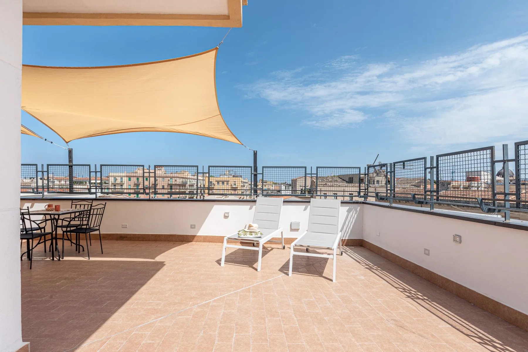 Una terraza en la azotea con asientos al aire libre bajo una cubierta de sombra.