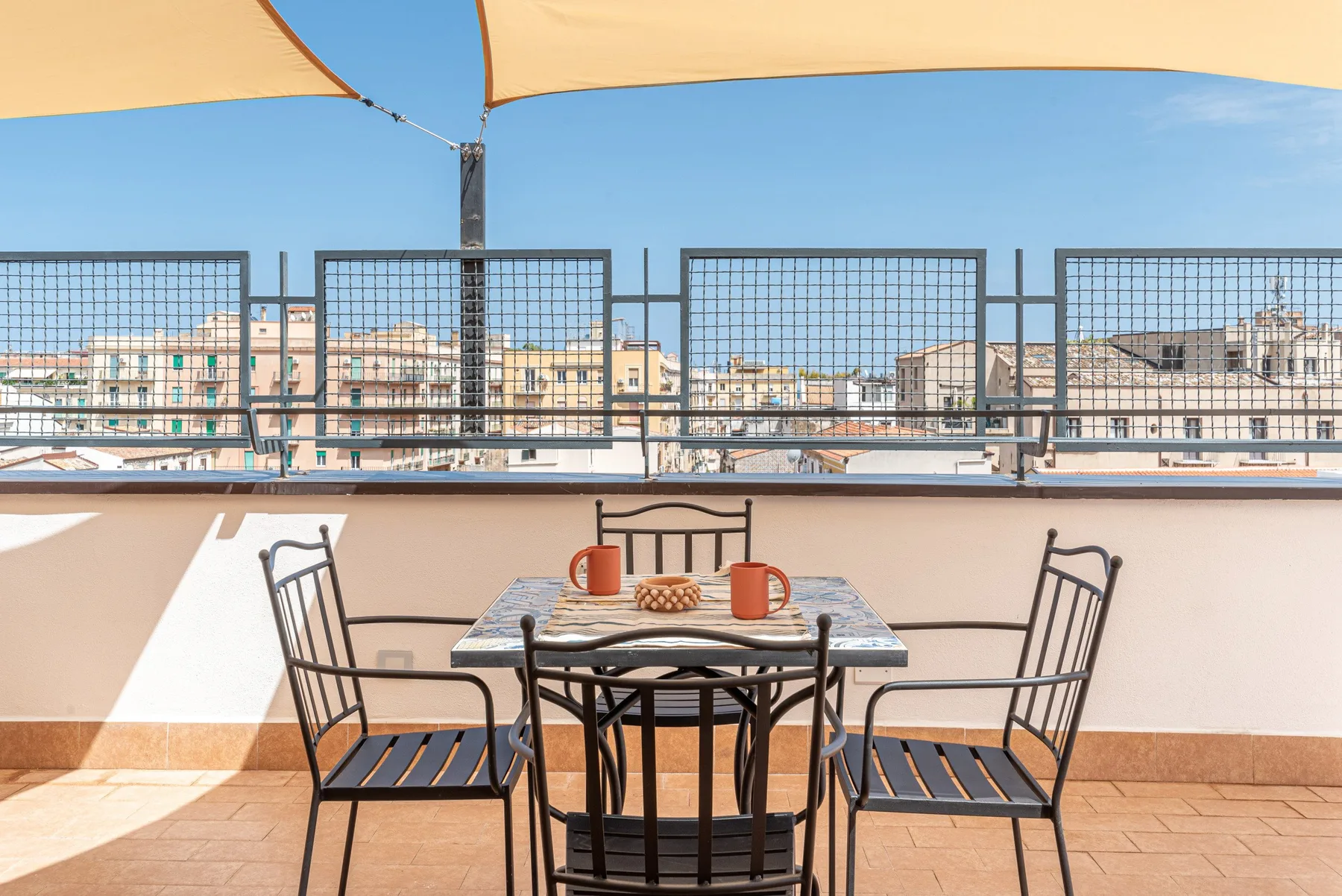Una zona de comedor al aire libre con mesa y asientos bajo un toldo.
