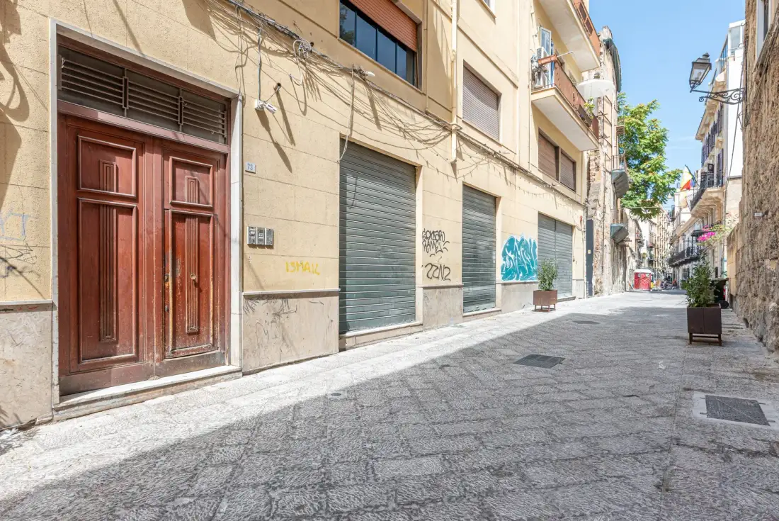 Una calle estrecha y pavimentada pasa entre edificios con comercios cerrados.