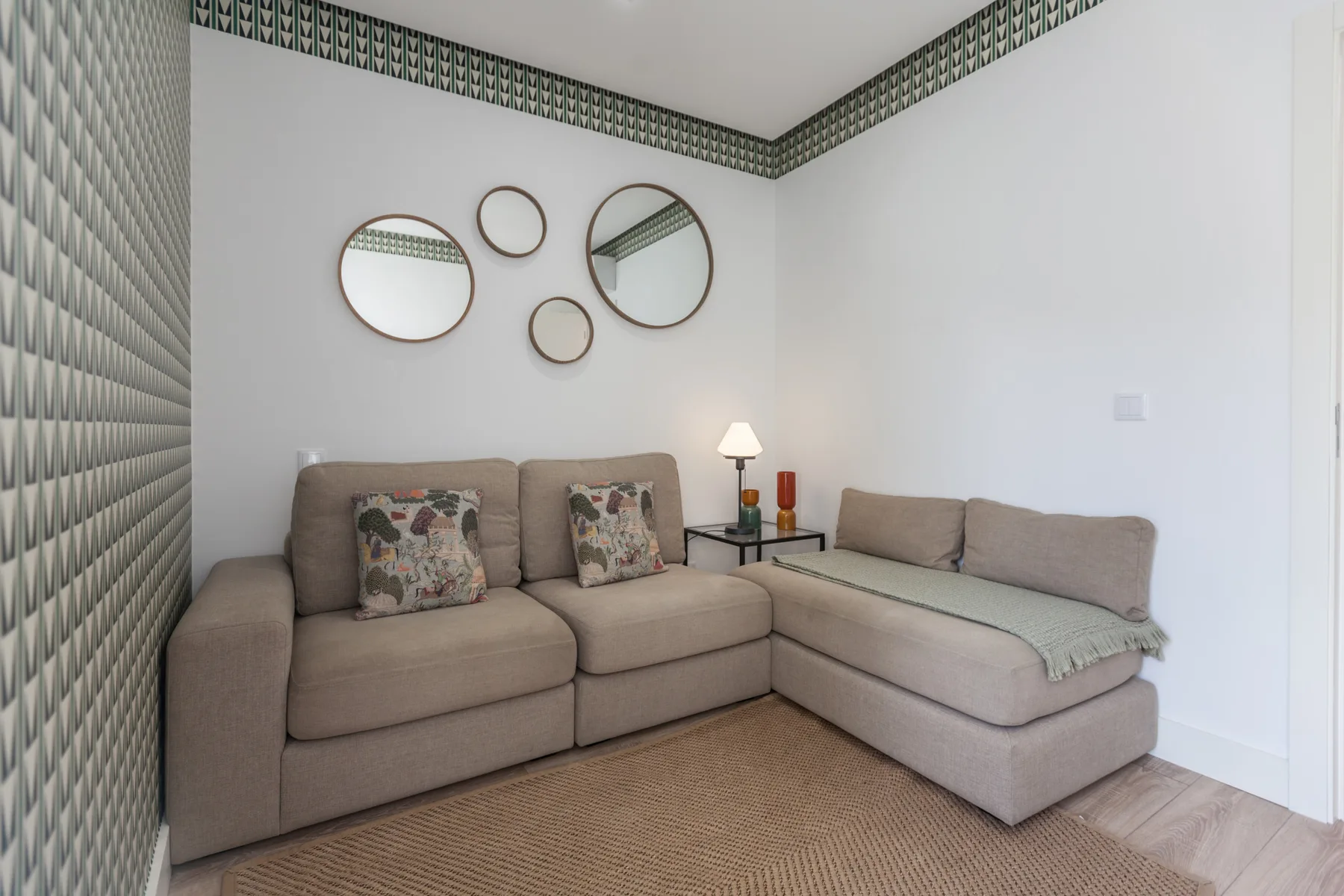 A living room with L-shaped seating, decorative mirrors, and a woven rug.