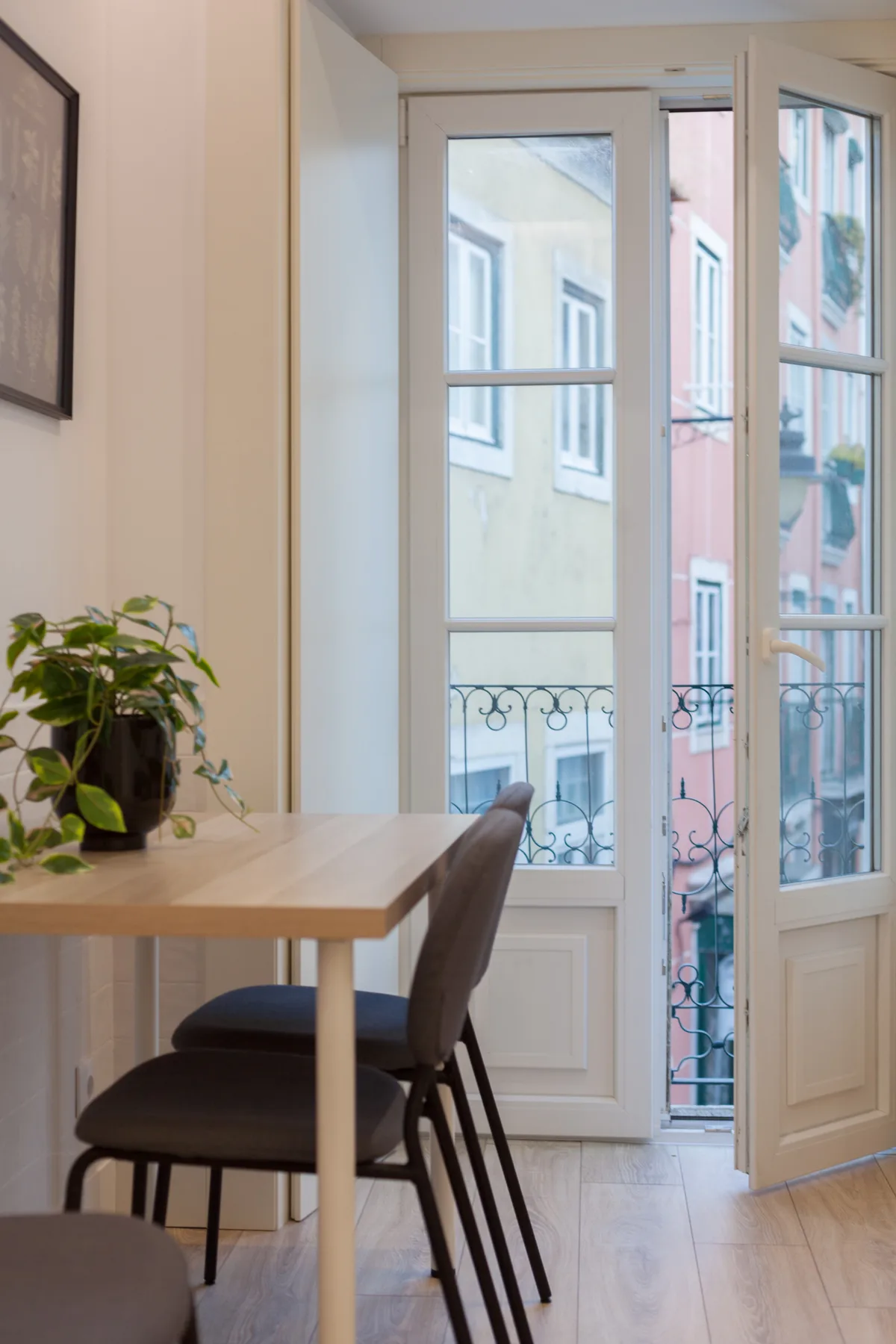 A small dining area by tall glass doors, with a table and seating.