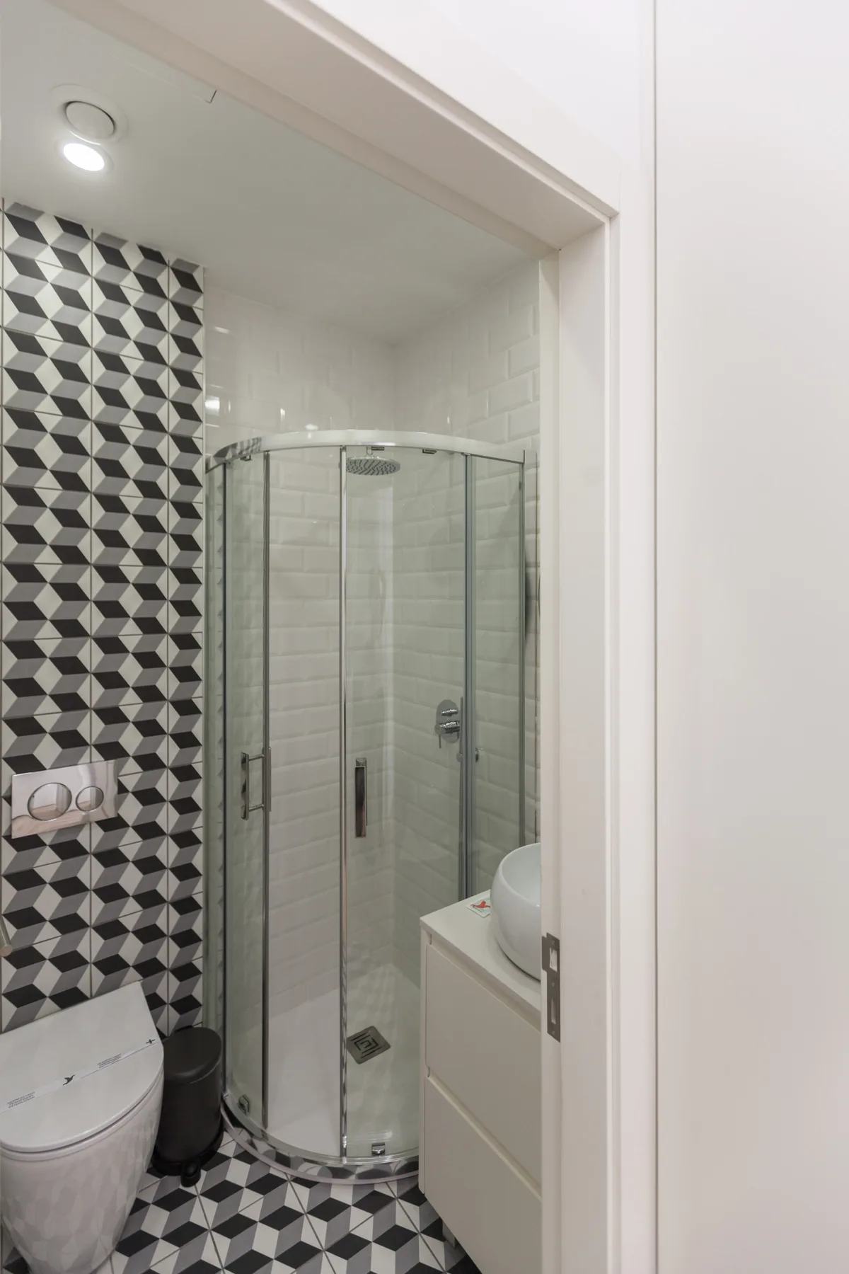A bathroom with a glass shower and bold geometric tile.