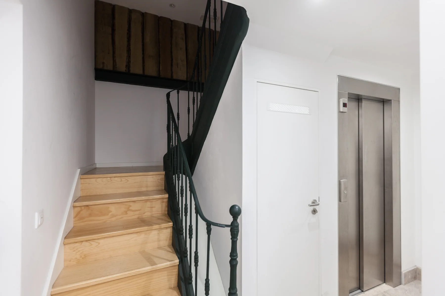 An interior stairway beside a closed door and elevator.
