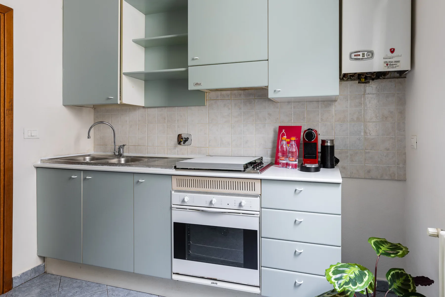 A compact kitchen with pale cabinets, a sink, and a stove.