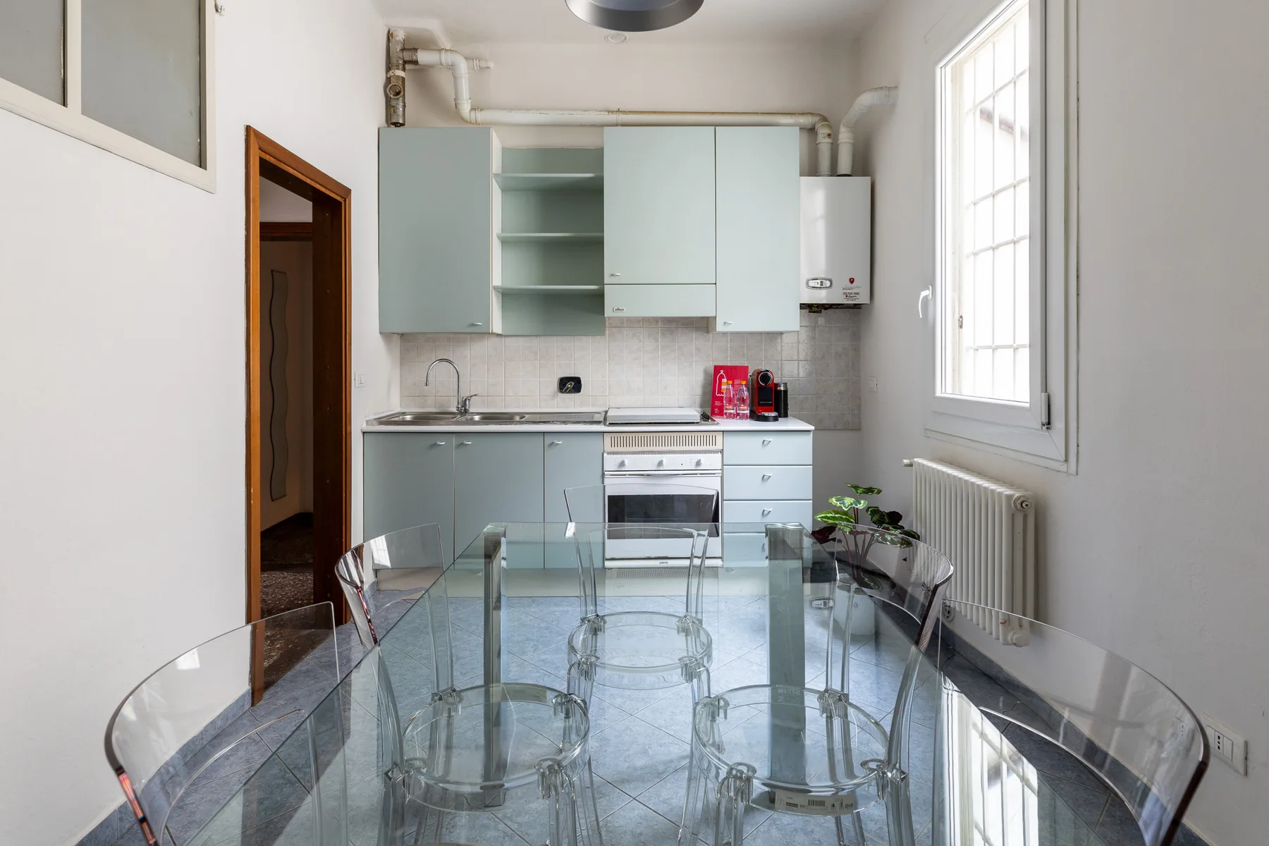 A bright kitchen with pale cabinetry and a glass dining table.