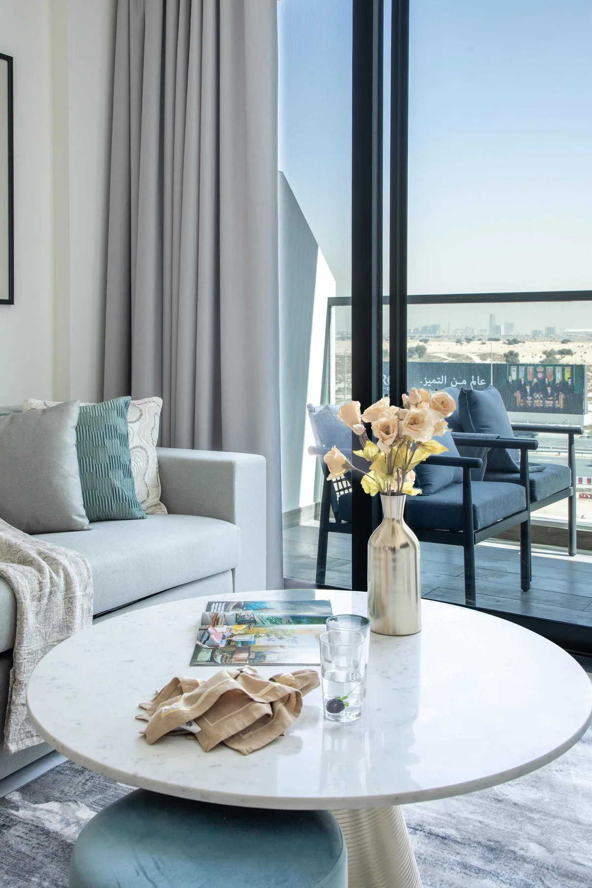 A bright living area with seating beside large glass doors opening onto a balcony.