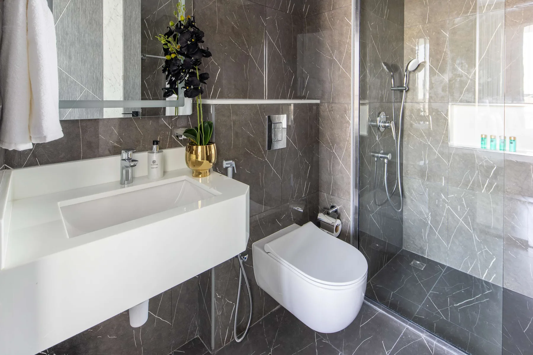 A modern bathroom with a sink, toilet, and glass shower.