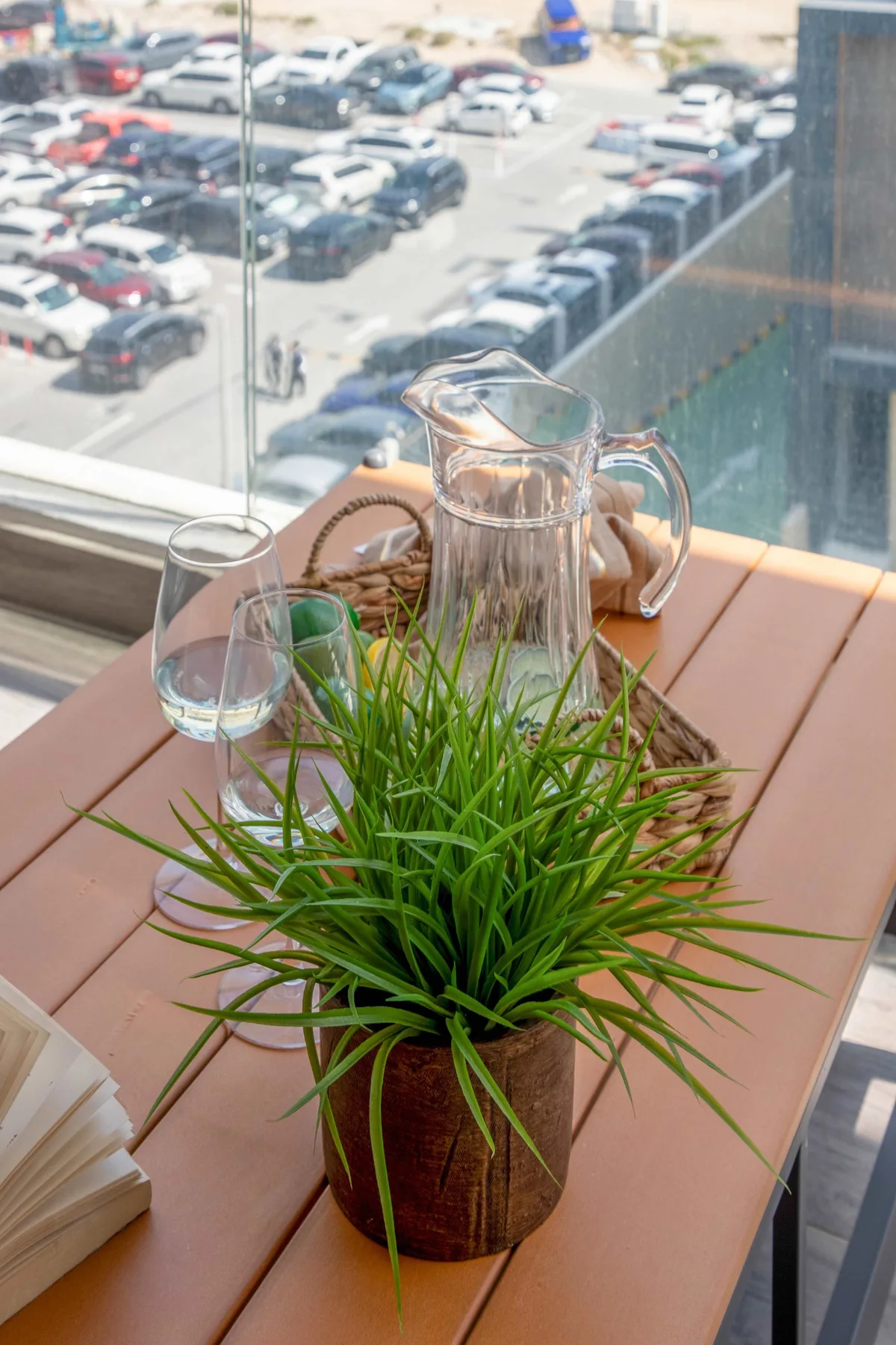 A table by a window holds a potted plant, a glass, and a water pitcher.