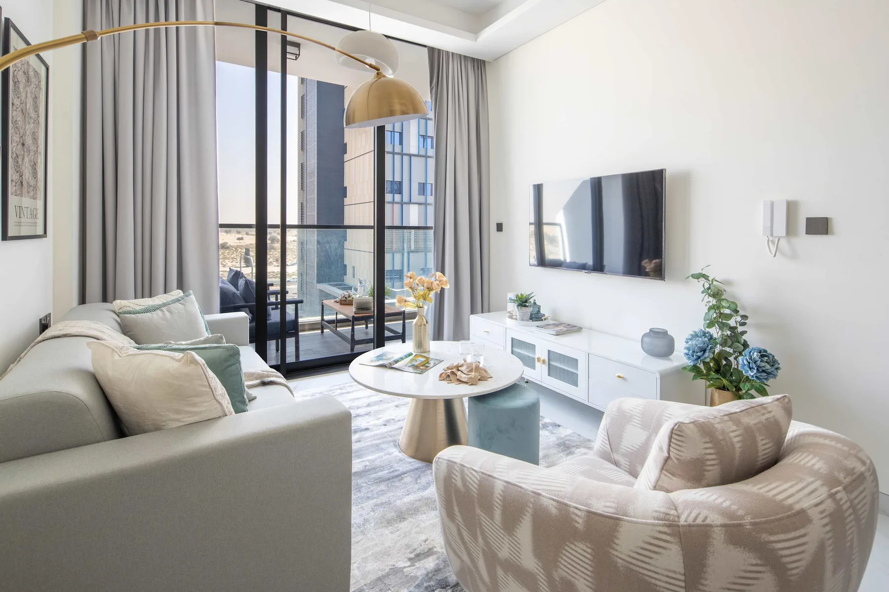 A bright living room with seating, a television, and large windows.
