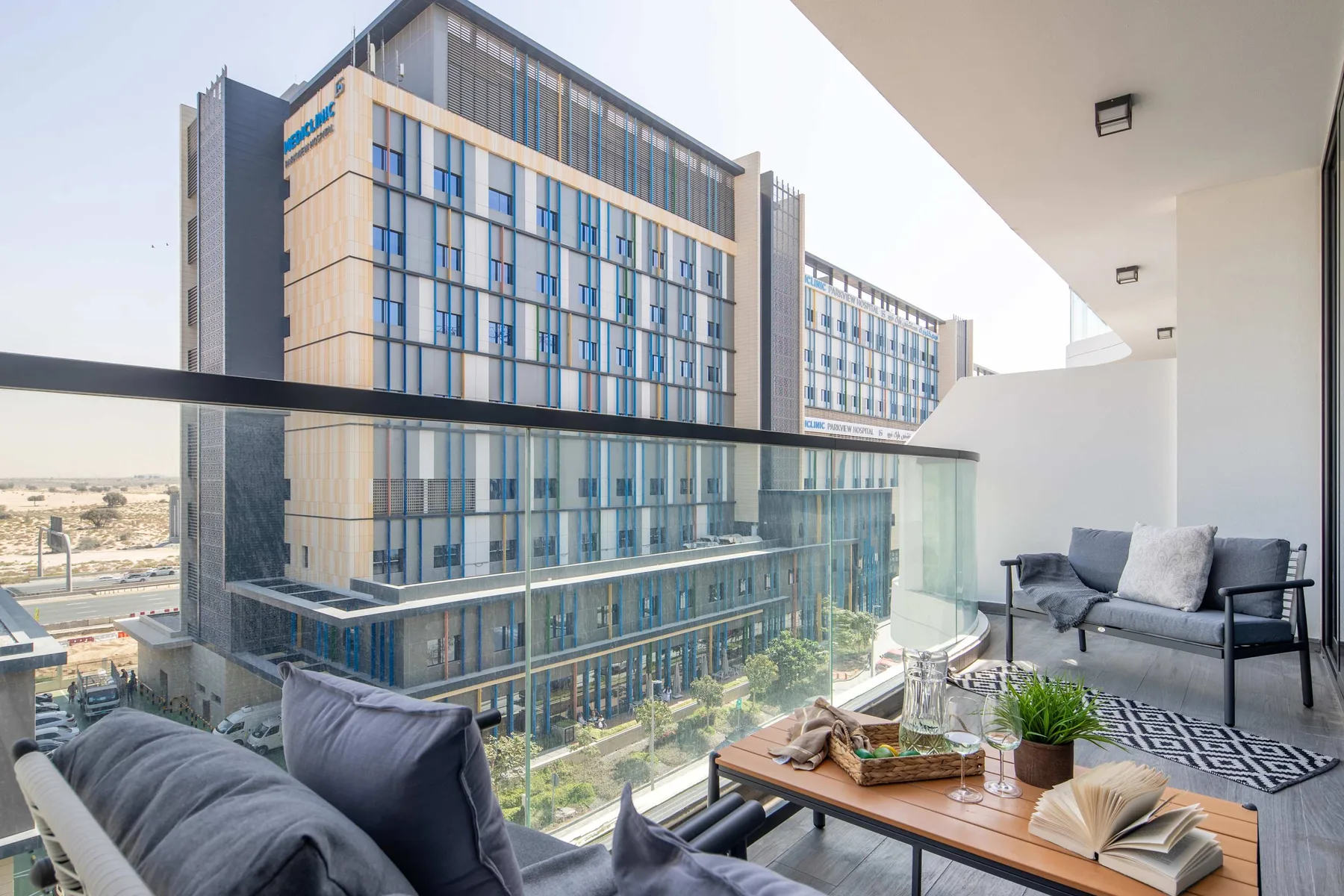 A balcony seating area overlooks a modern glass-fronted building.